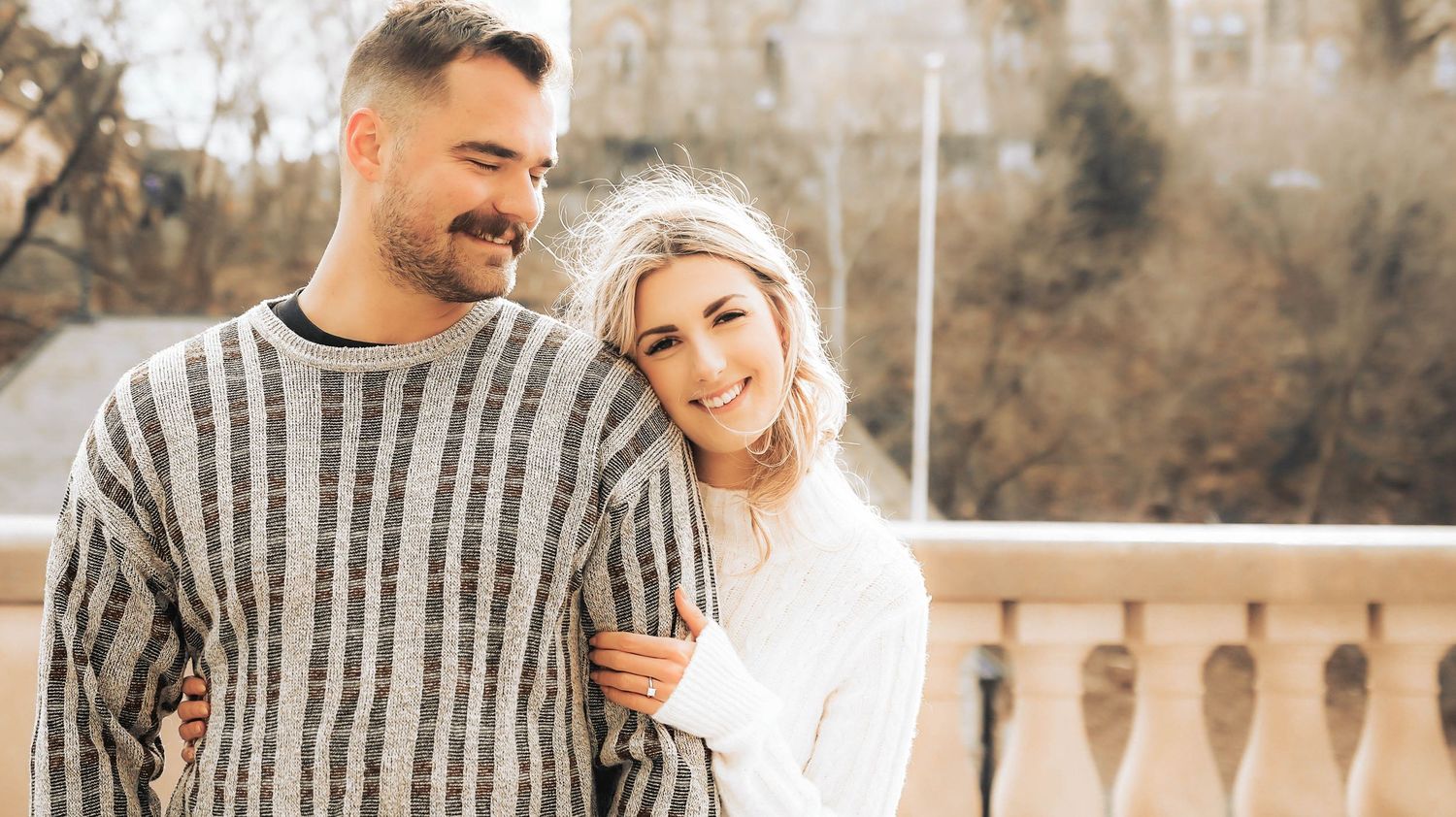 A romantic couple shares tender moments in a winter outdoor setting during an engagement photo session.