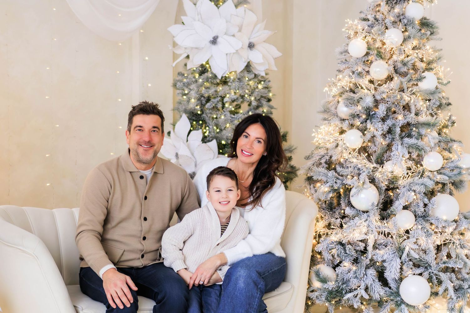 Family holiday portrait session with flocked Christmas tree and white decorations.