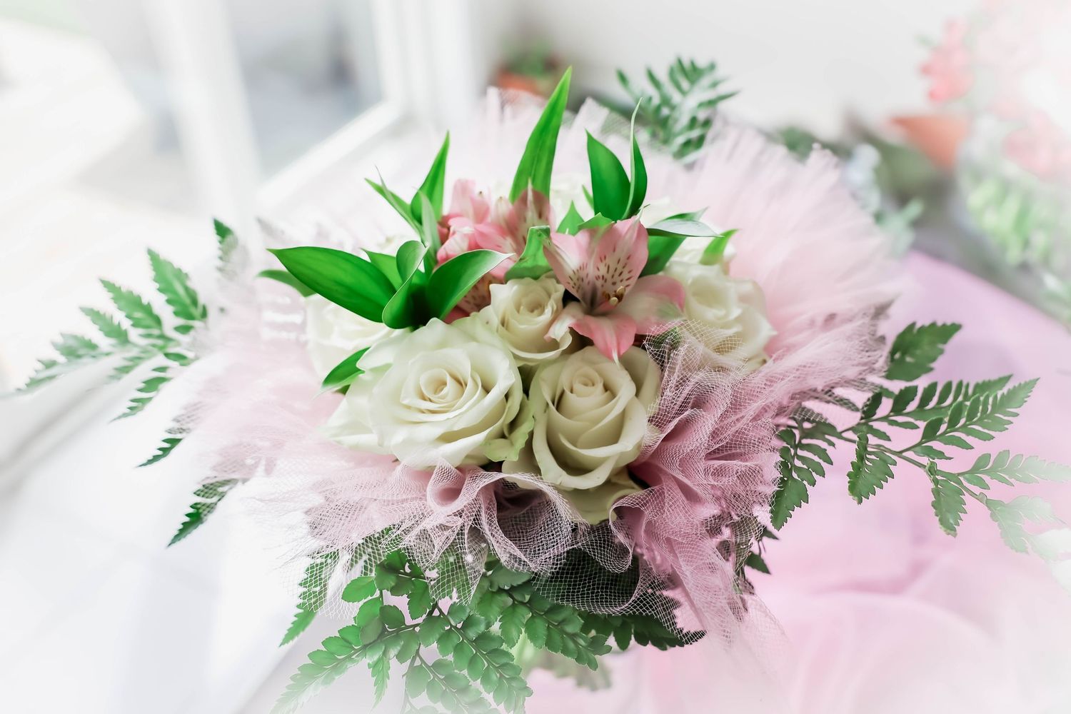 Soft pink and white floral arrangement with delicate ferns and roses.