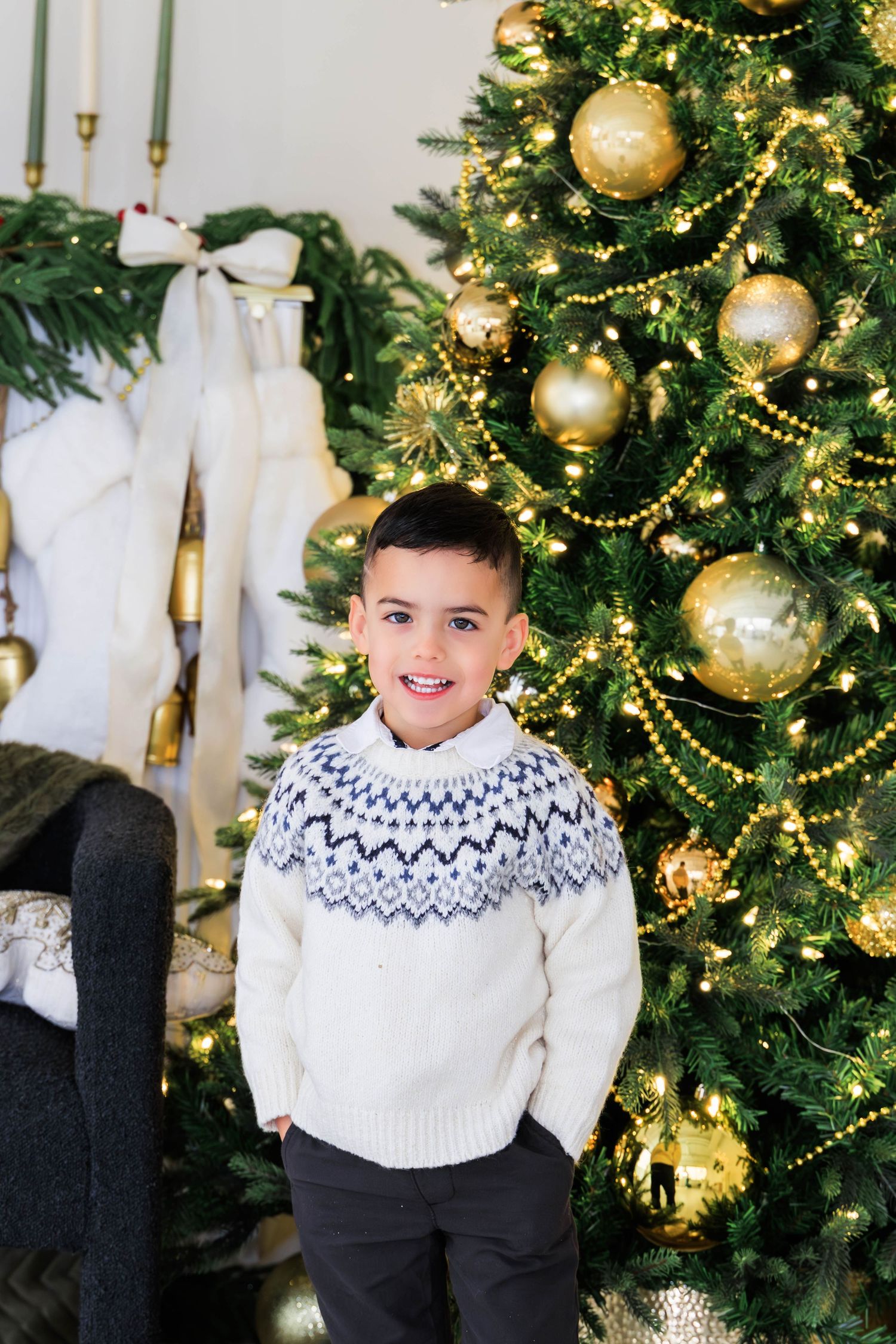 Holiday portrait with decorated Christmas tree and gold ornaments in background.