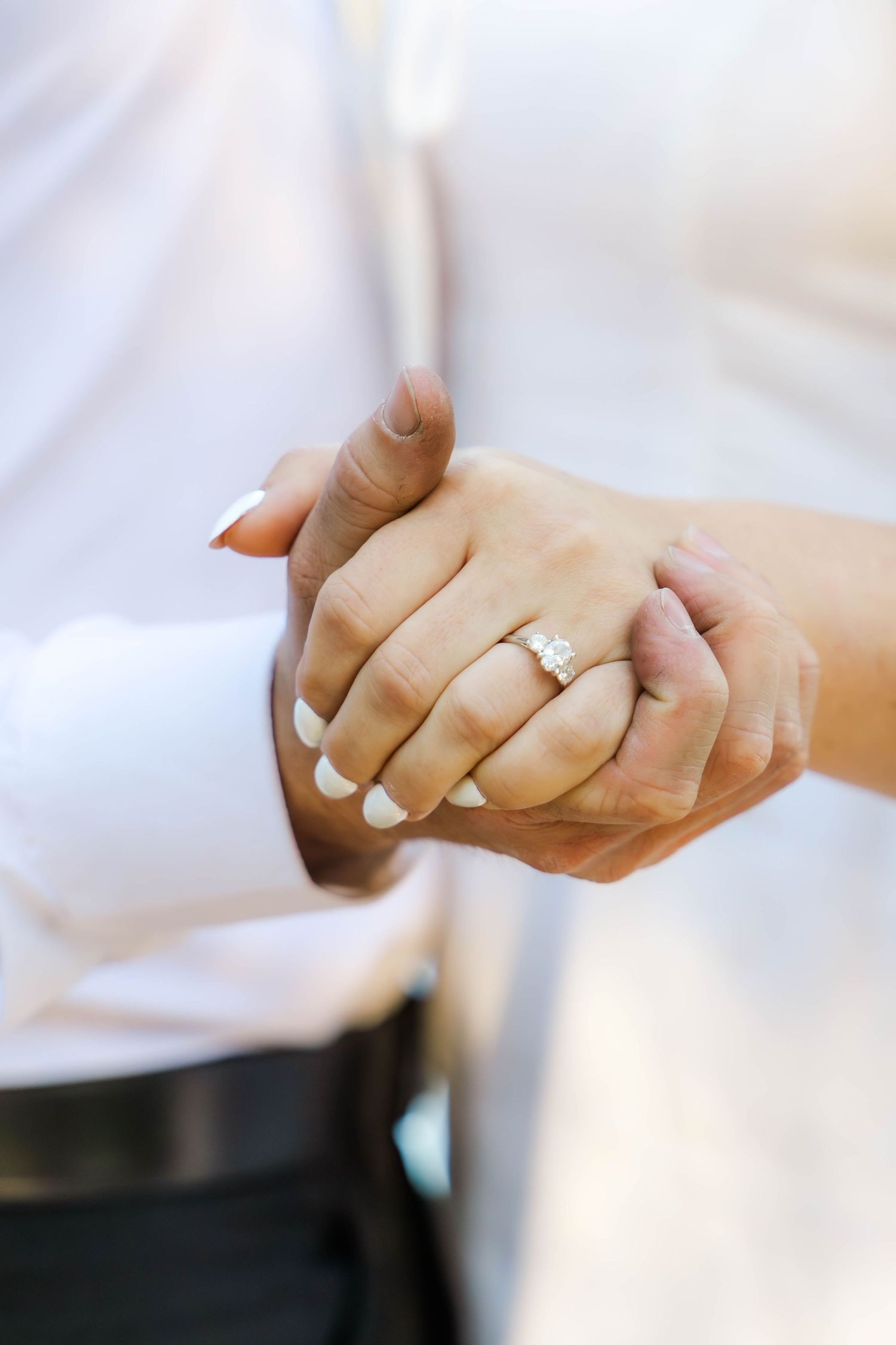Close-up of hands performing elegant gestures against a soft white background.