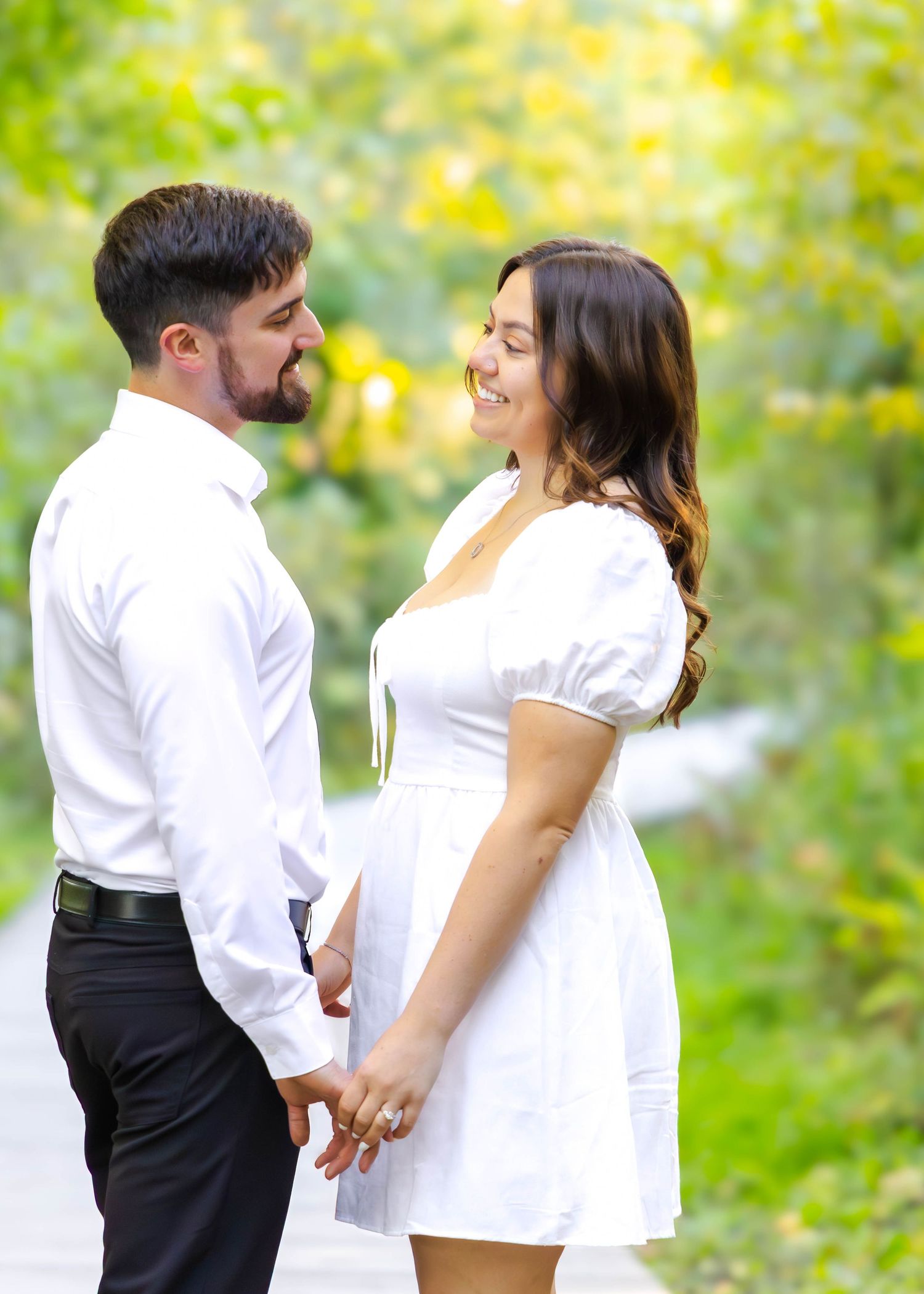 Couple in coordinated white and black attire share intimate moments on an outdoor walkway.