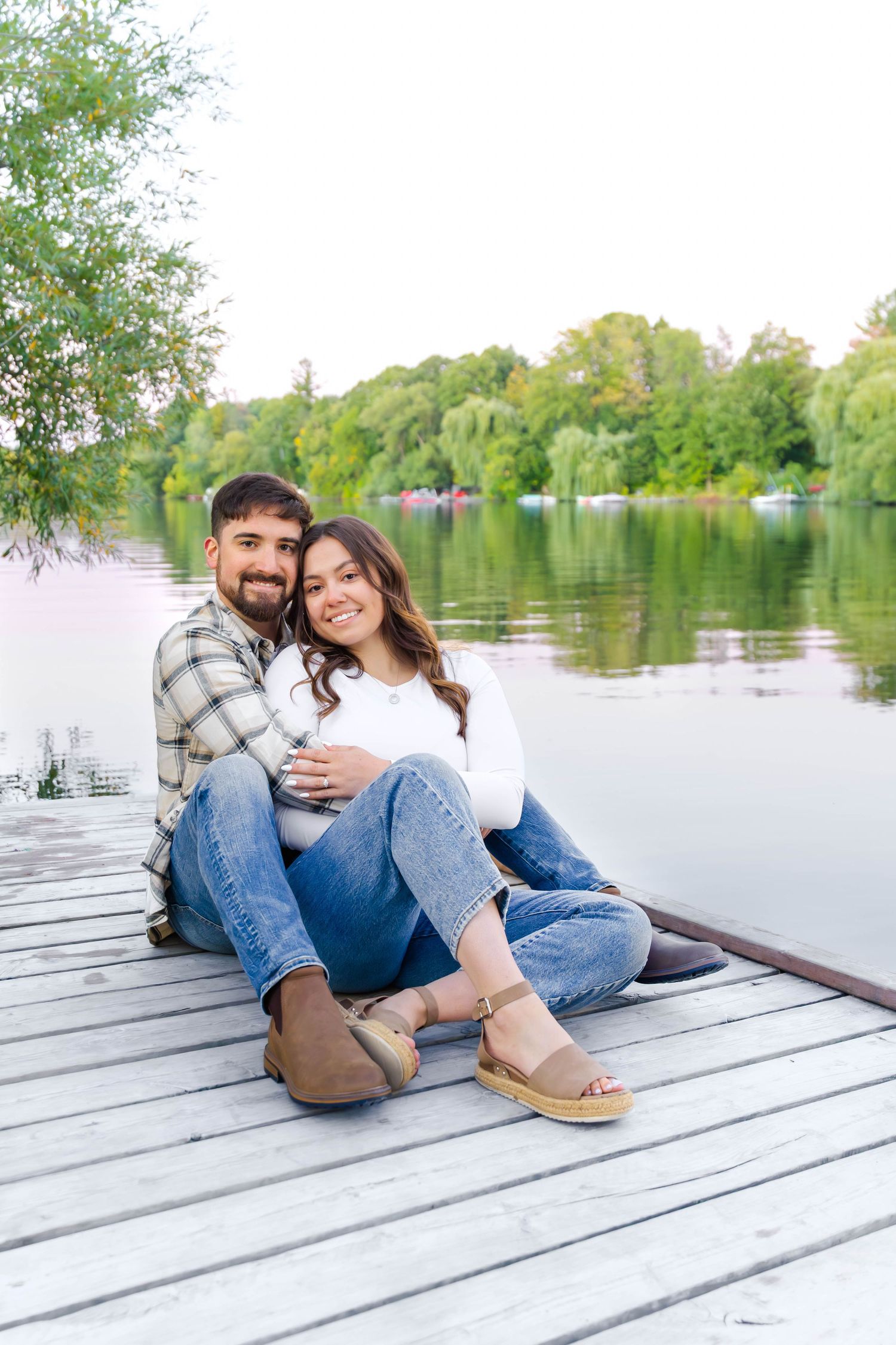 Couple relaxing on wooden dock by tranquil lake during sunset photo session.