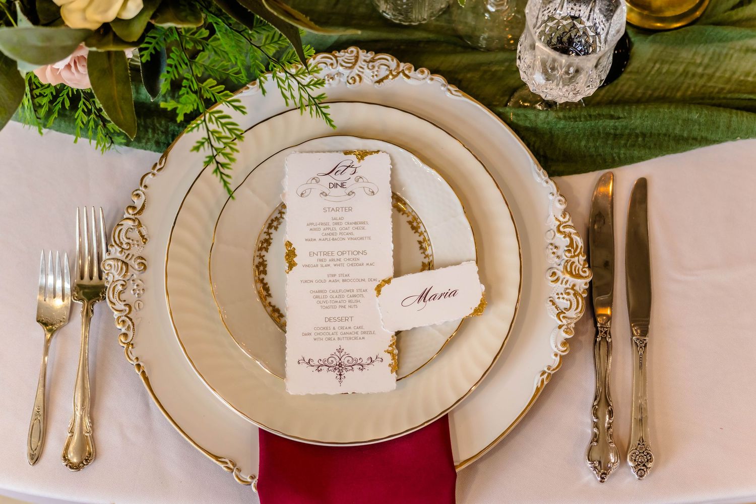 Elegant wedding reception table setting with gold-rimmed plates, crystal glassware, and delicate floral arrangements.