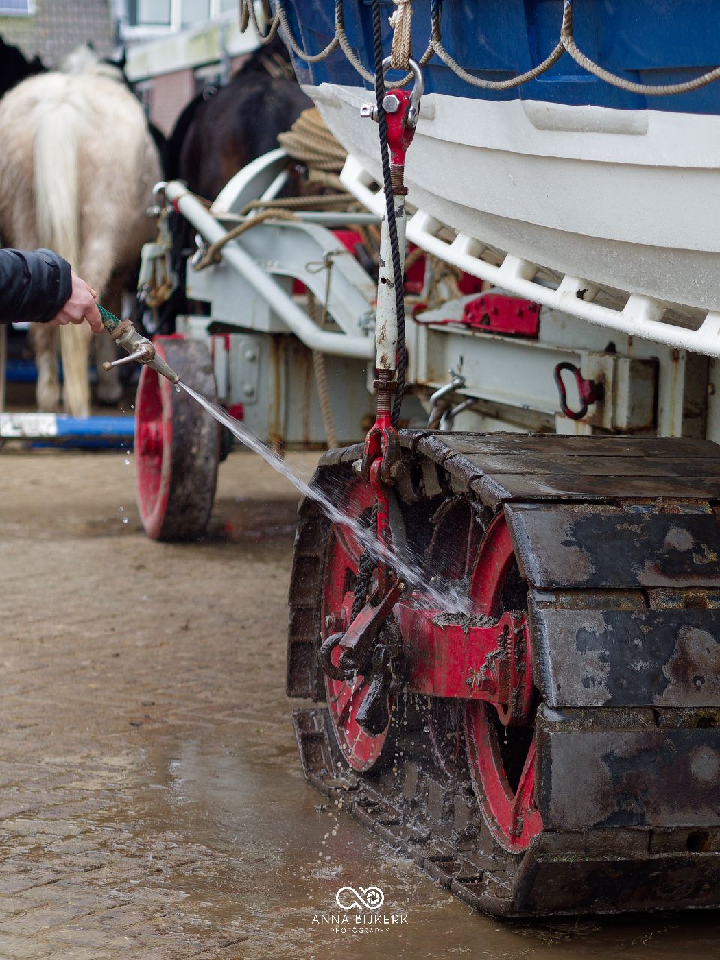 Close-up view of muddy tractor wheels and plough equipment working in wet agricultural field conditions.