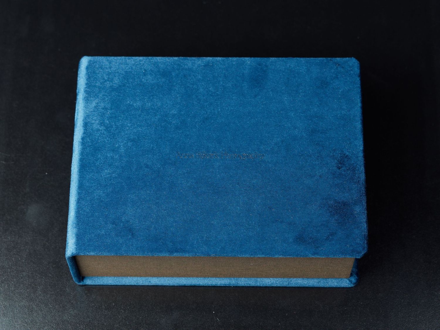 Blue hardcover book lying flat on dark surface.