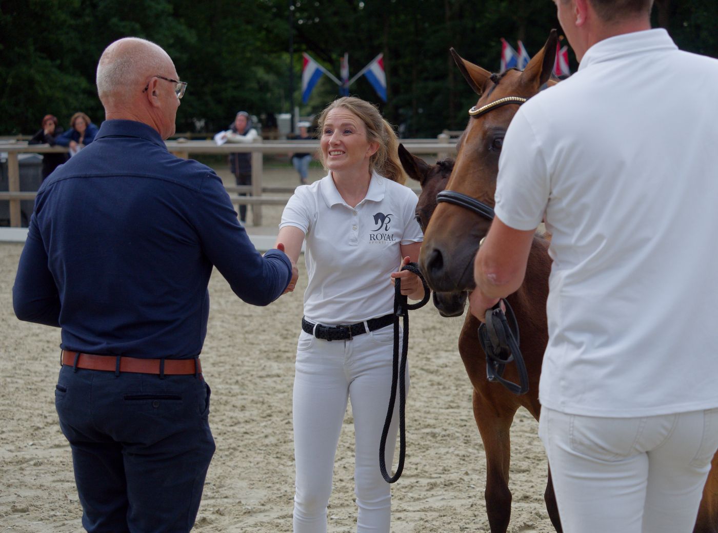 Handlers in white uniforms present horses during a formal equestrian show event.