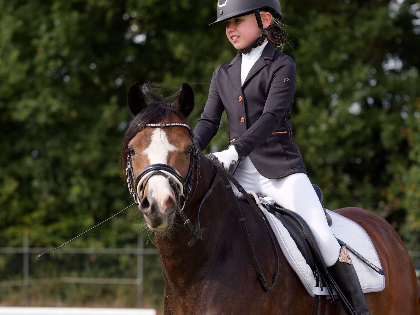 Horses and riders execute dressage movements in formal attire on a grass course.