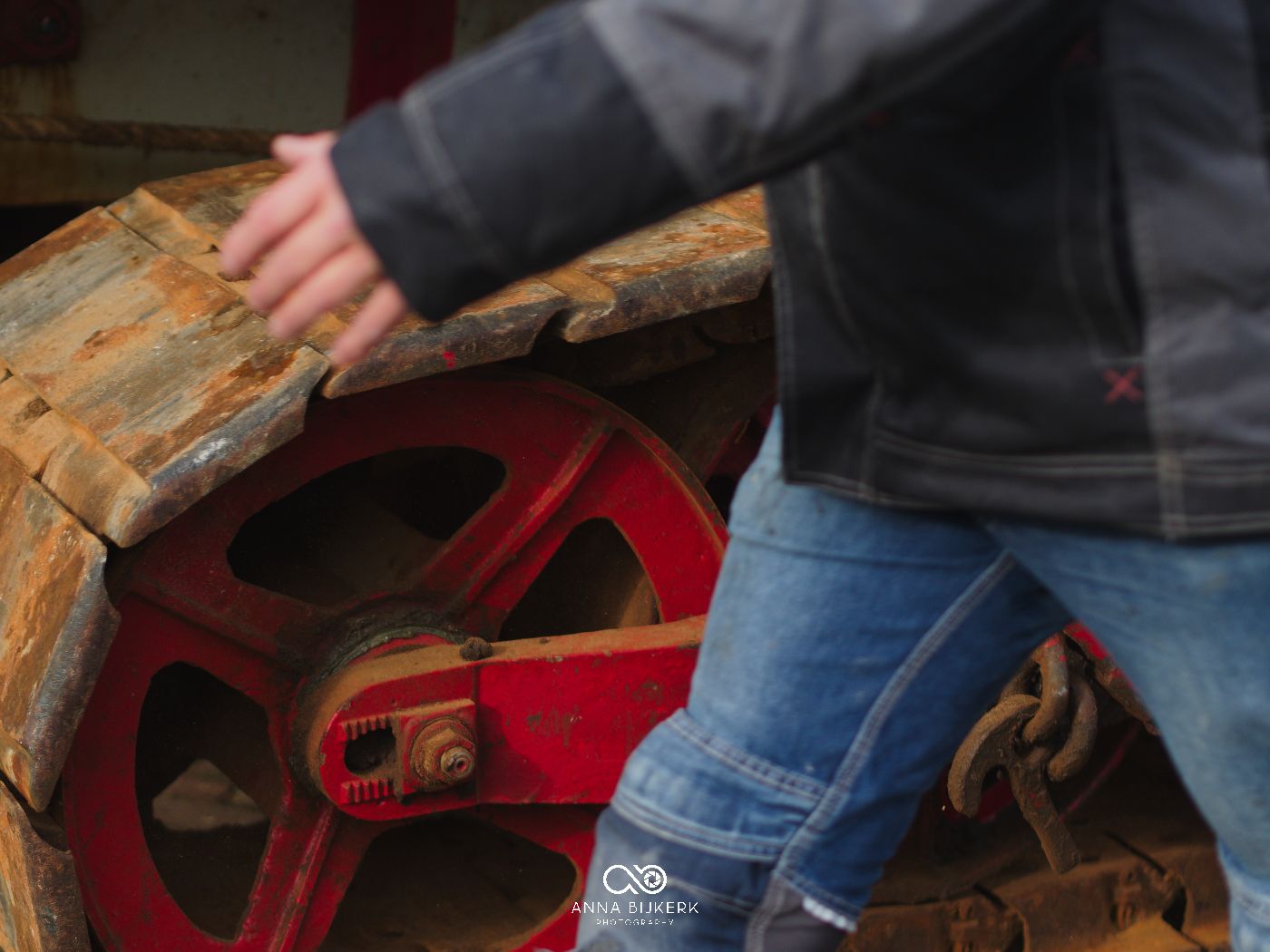 Close-up of hands using a red metal tool to repair or maintain machinery parts.