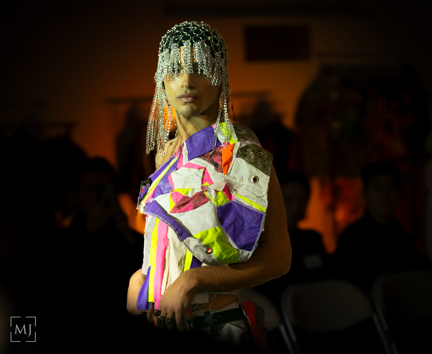 A dark performance scene with colorful geometric light projections and silhouettes creating a dramatic atmosphere. Fashion Photographer