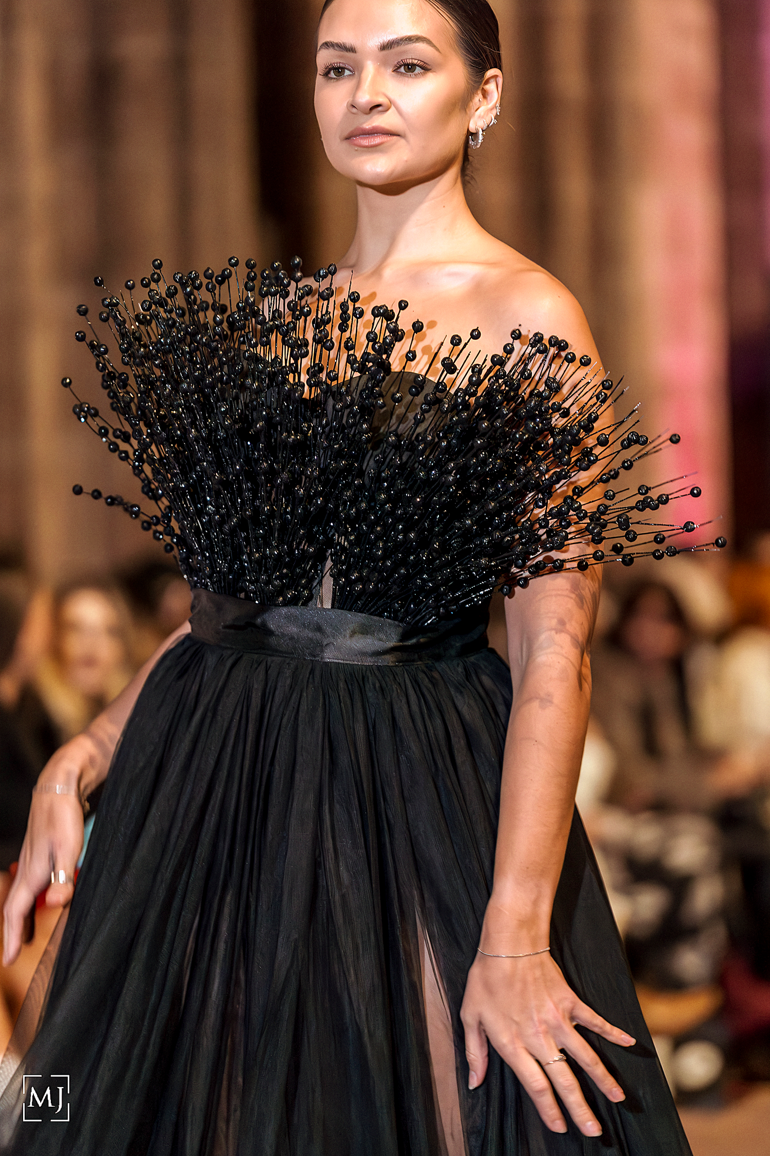 Fashion model wearing dramatic black strapless dress with voluminous textured neckline detail on runway. Fashion Photographer Martin Japheth
