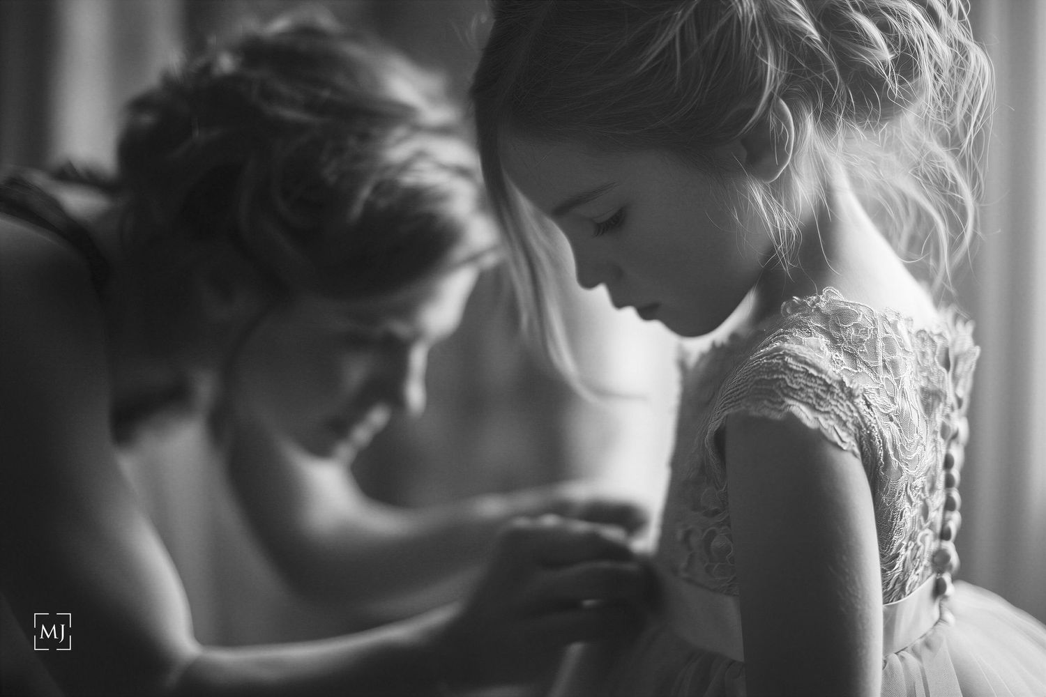 Intimate black and white moment of wedding dress preparation in soft window light. Wedding Photographer Martin Japheth