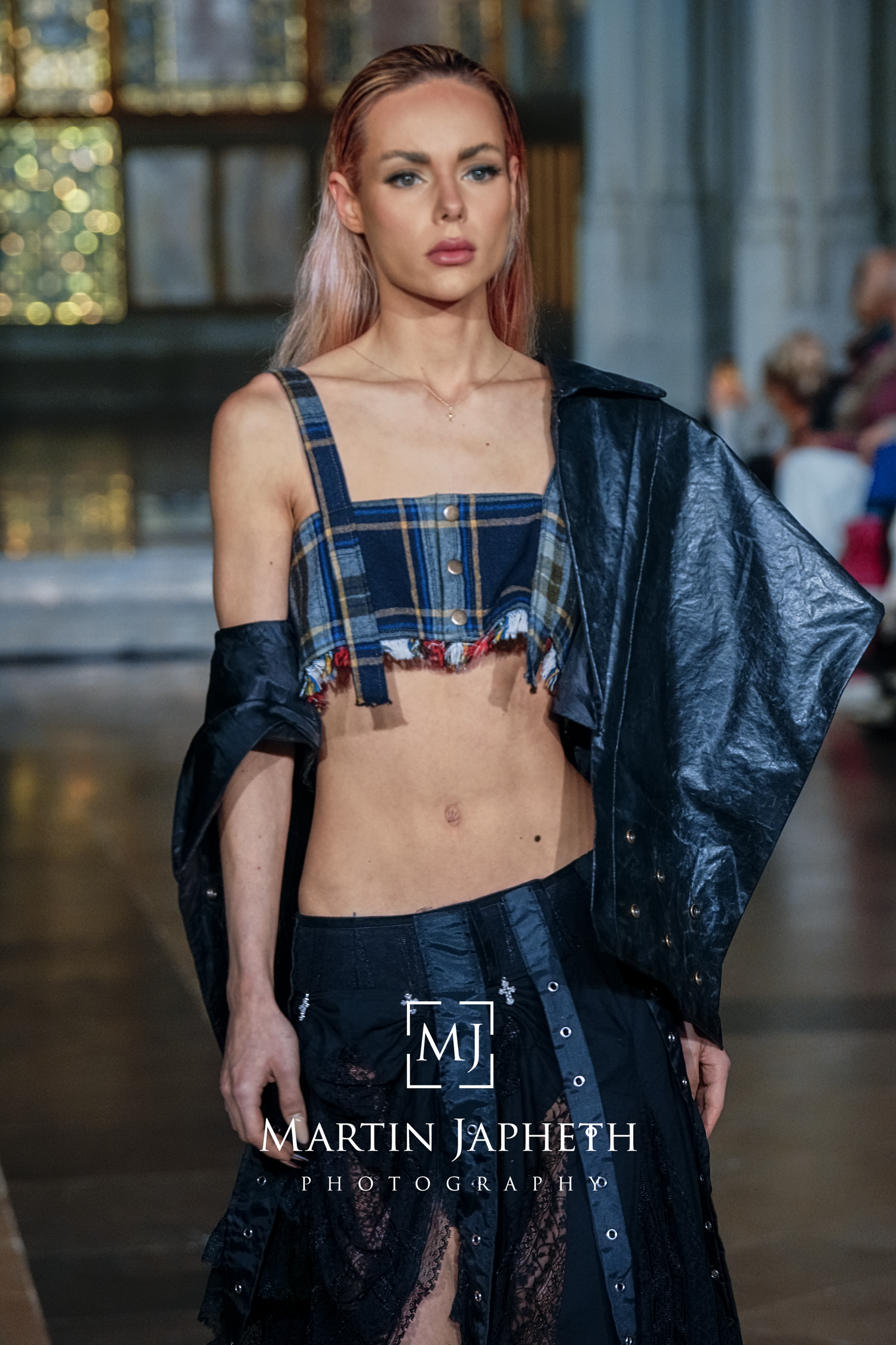 Model showcasing avant-garde navy blue fashion design with deconstructed elements on catwalk.