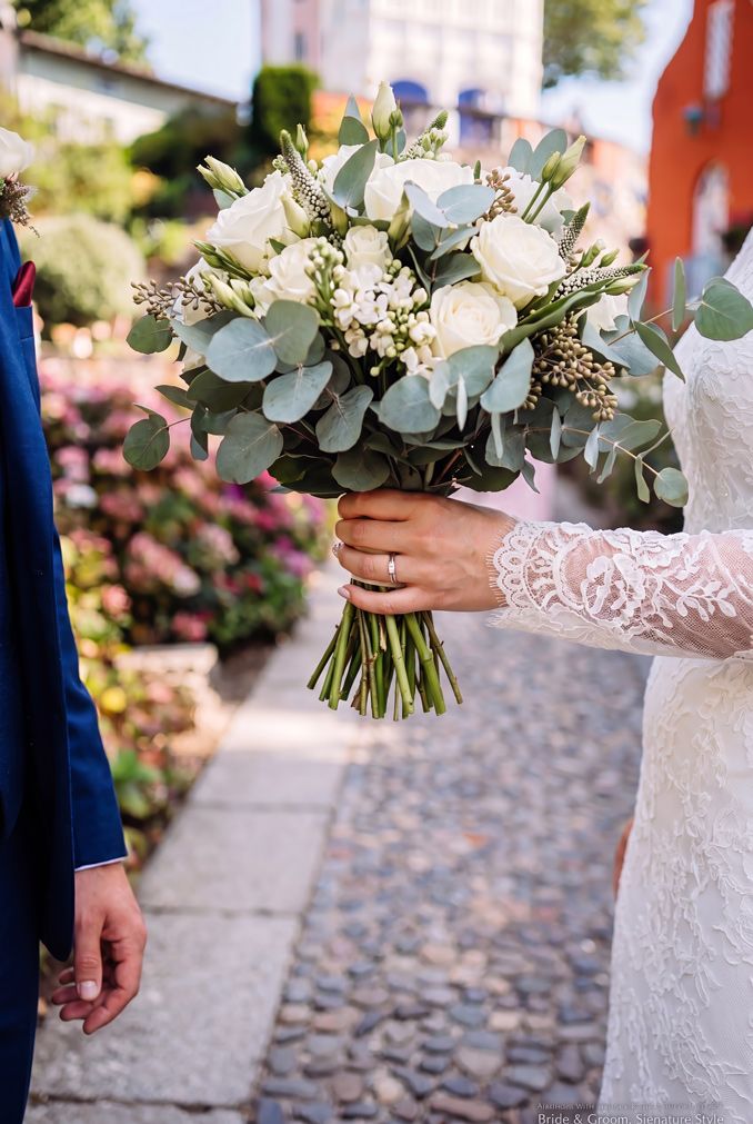 Bride in lace dress holding white rose and eucalyptus wedding bouquet Portmeirion Village. Wedding by Martin Japheth Photography.