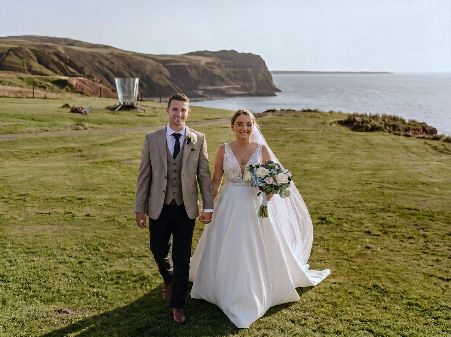Bride and groom holding hands on Nant Gwrtheyrn cliffside overlooking Porthdinllaen. Martin Japheth Photography