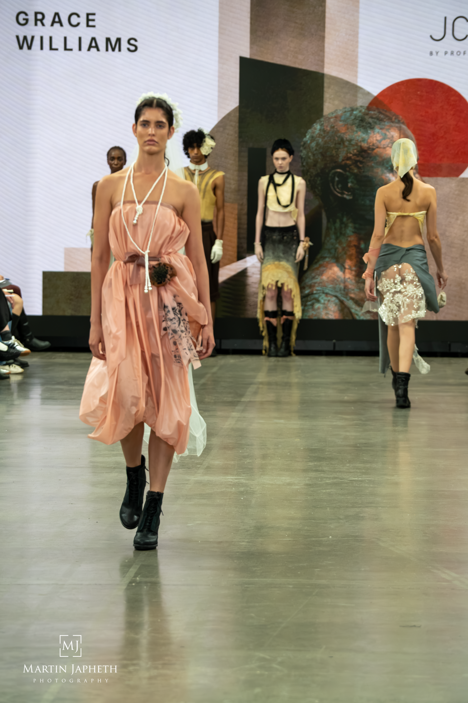 Grace Williams fashion show featuring models in flowing pink dress with floral accents walking the runway. Martin Japheth Photography