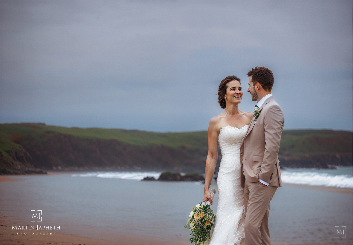 A bride and groom share a romantic moment on Rhoscolyn beach Wedding Photographer Martin Japheth..