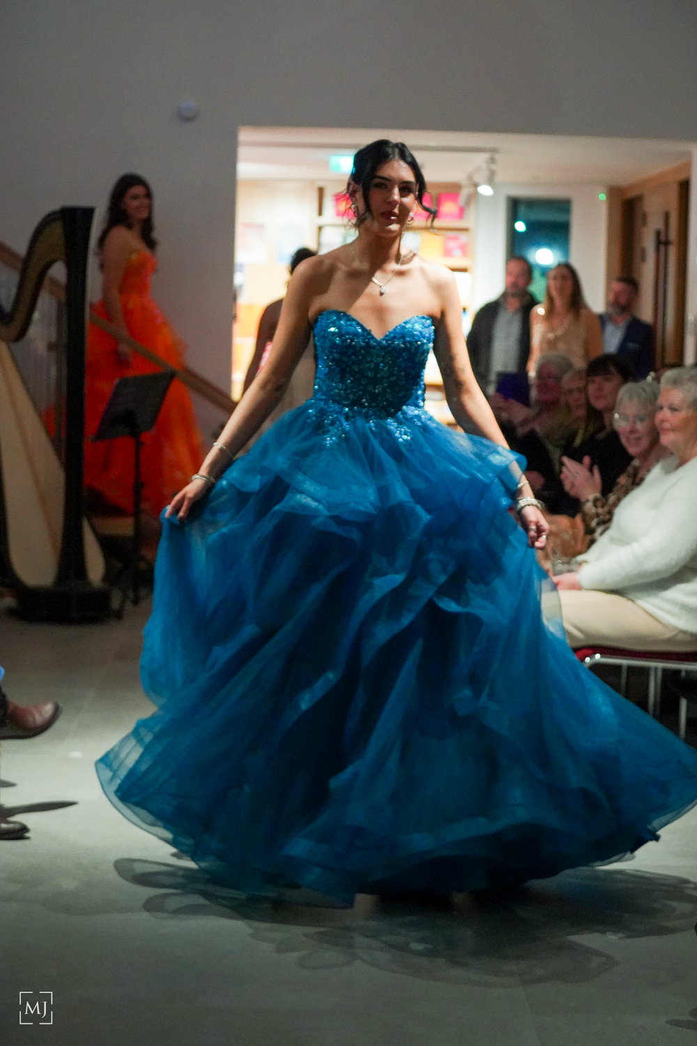 A model twirls in a sparkling turquoise ball gown during a fashion show performance. Fashion Photographer Martin Japheth