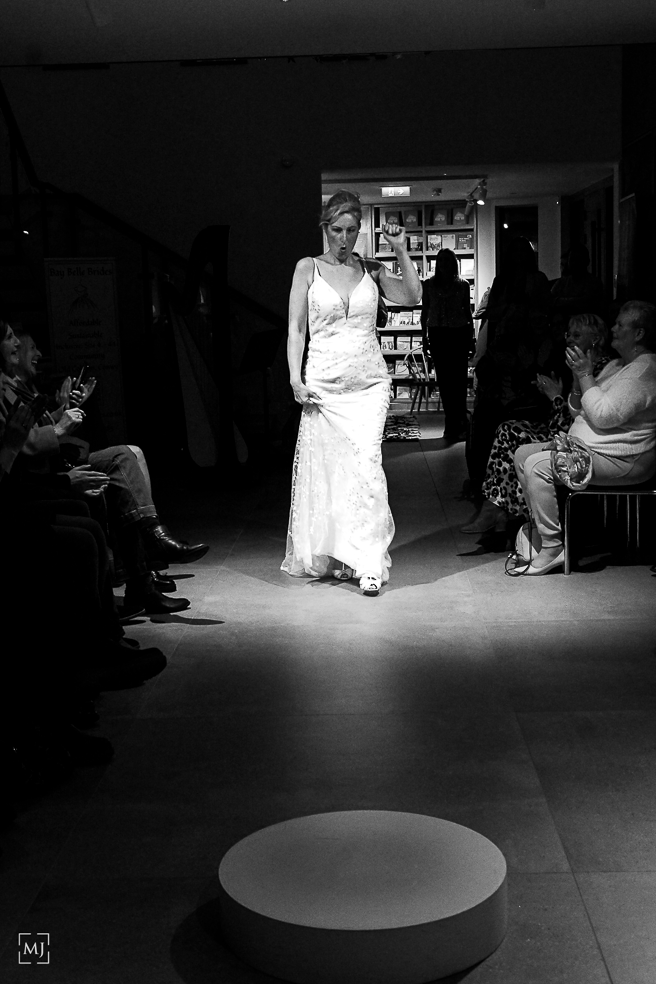 A dramatic black and white performance sequence shows a figure in white moving across a darkened stage area.