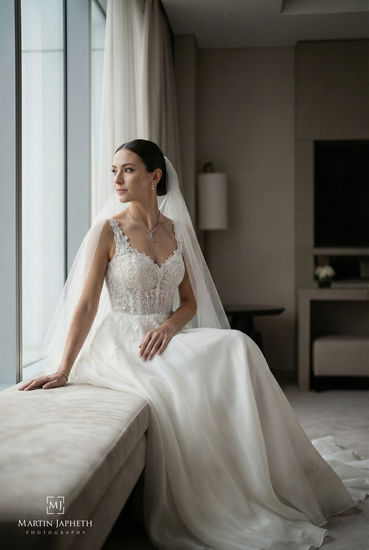 Elegant bride in St. George's Hotel by window in soft natural light, captured by Martin Japheth Photography.