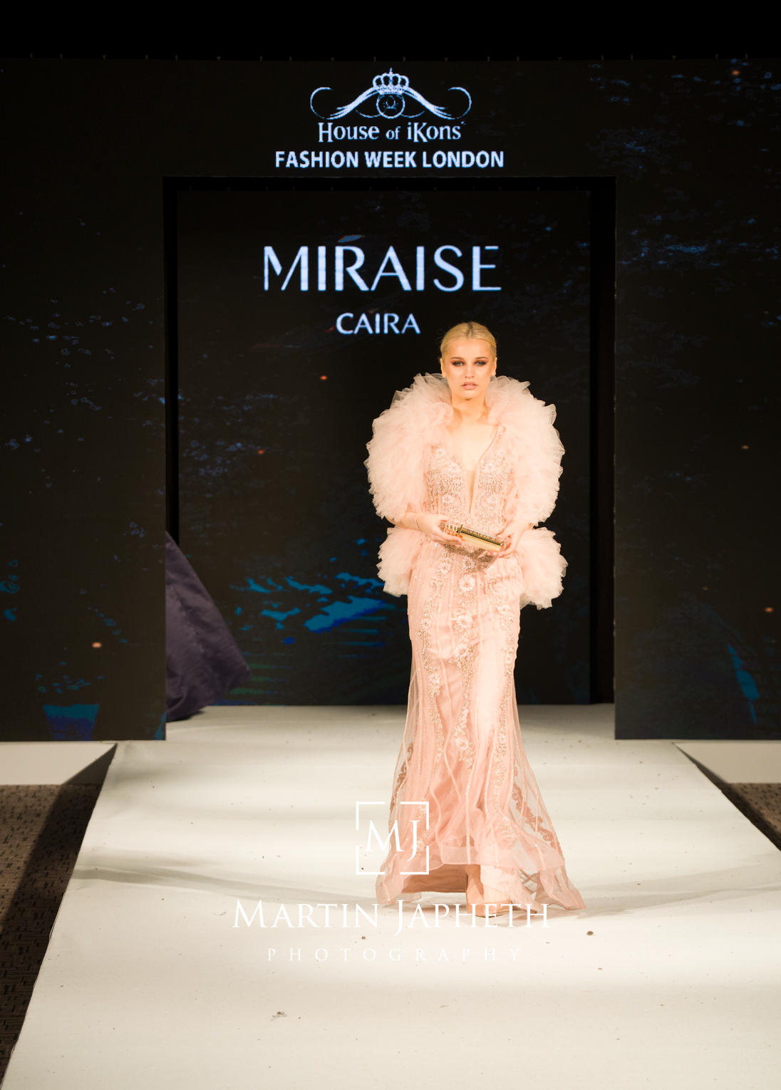 A model walks the runway in a voluminous peach-colored ruffled gown during Fashion Week London.