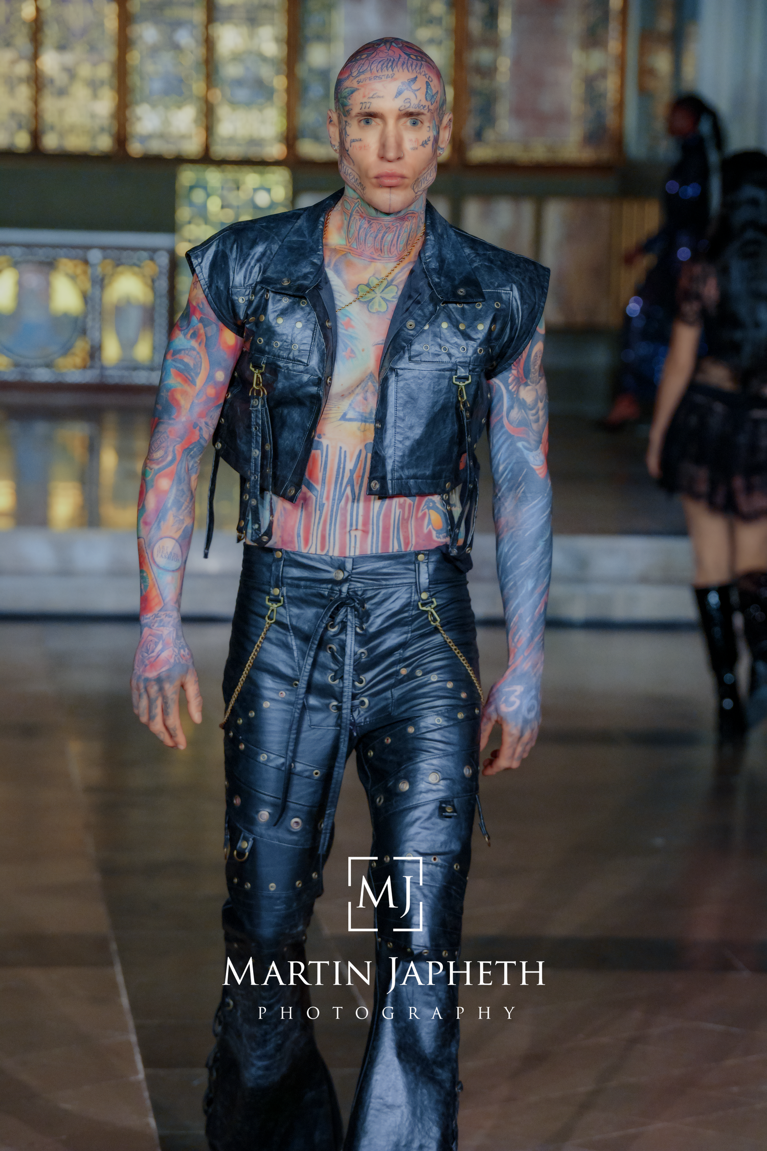 Alternative fashion show displaying black leather overalls and vest designs with punk aesthetic details.