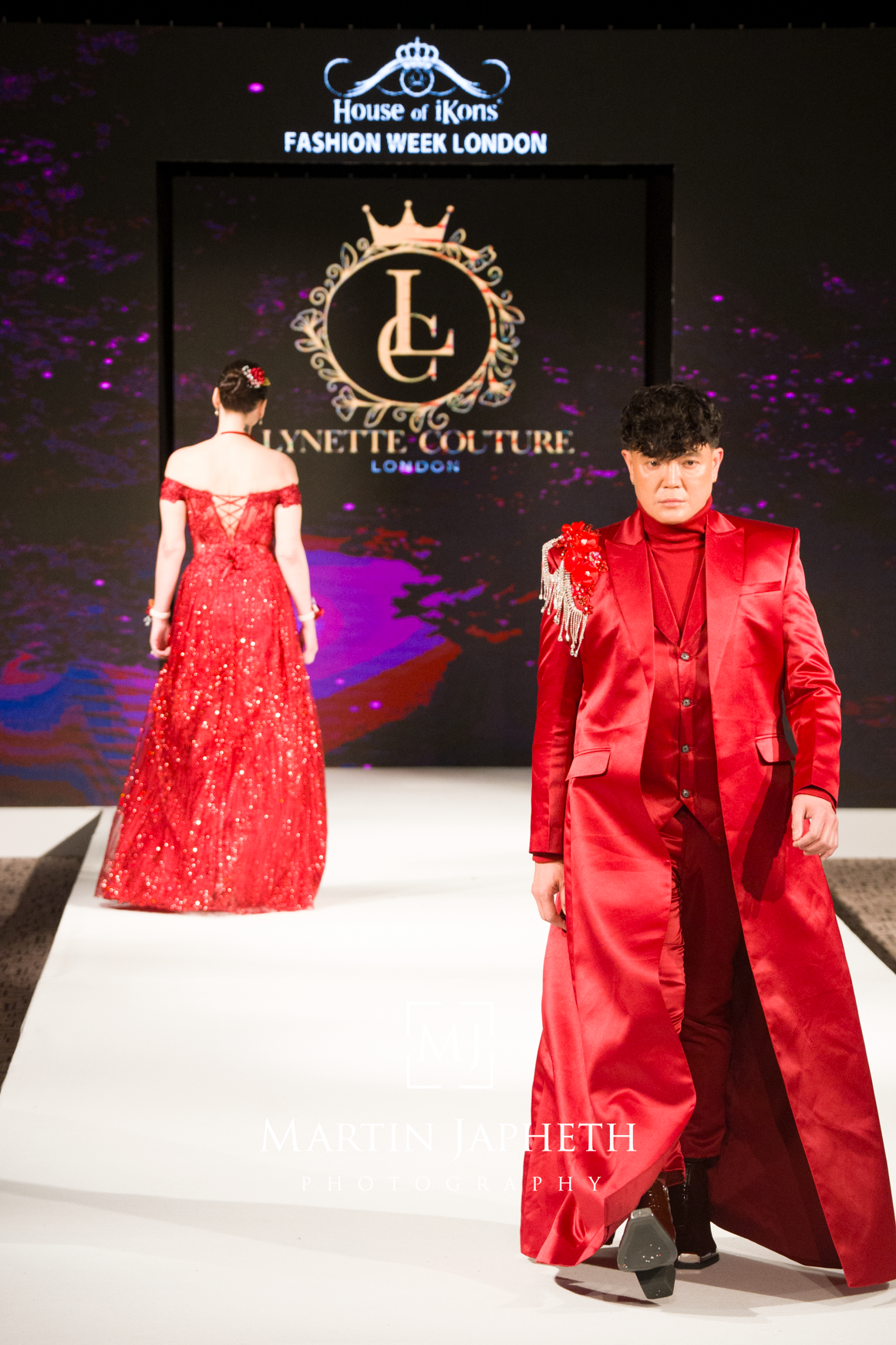 Models showcase matching red formal outfits on the runway at House of iKons Fashion Week London.