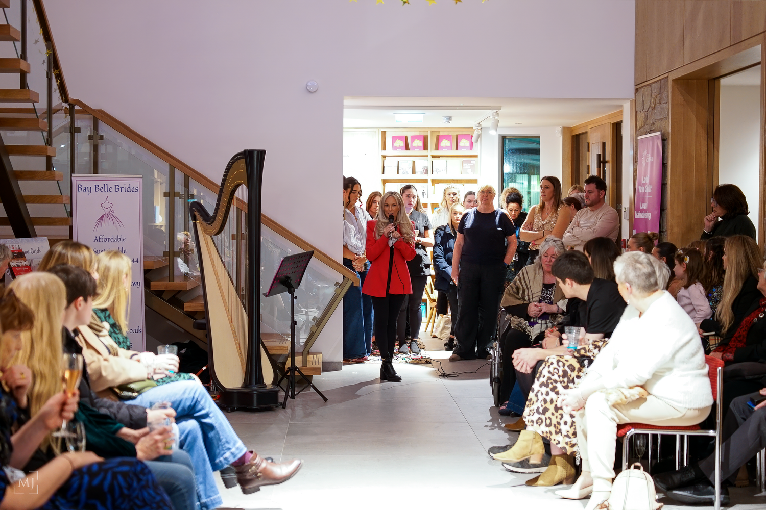 A crowd gathers in a bright indoor space to watch a harp performance during a cultural event.