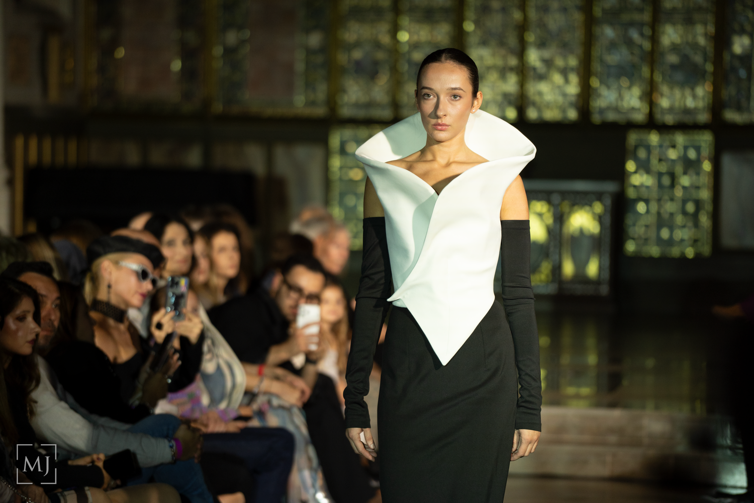Fashion show models showcase elegant black and white designer outfits on a sleek runway.