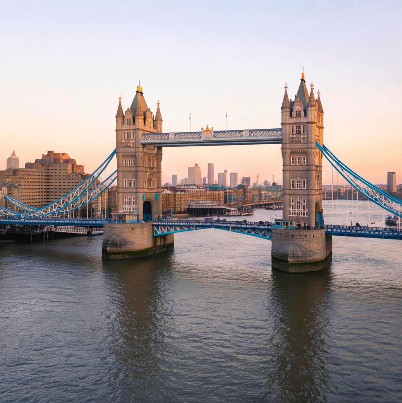 Tower Bridge spanning the River Thames at golden hour sunset with London city skyline in the background.