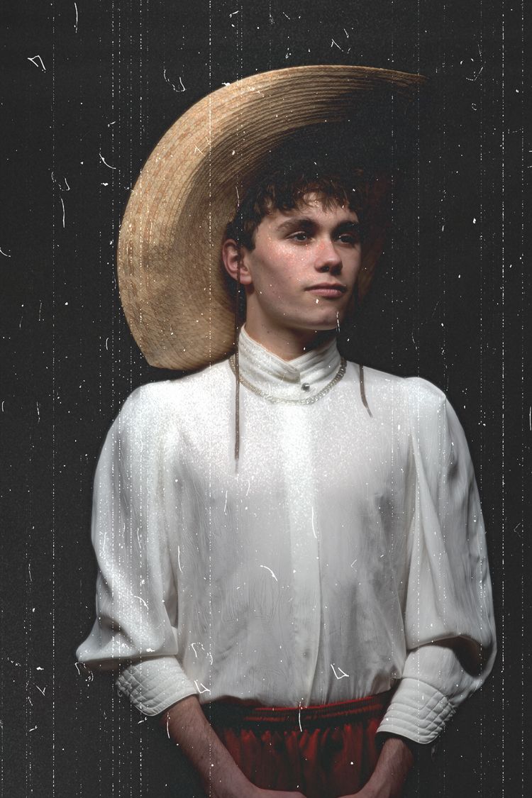 Portrait against dark background with golden halo effect and white turtleneck.