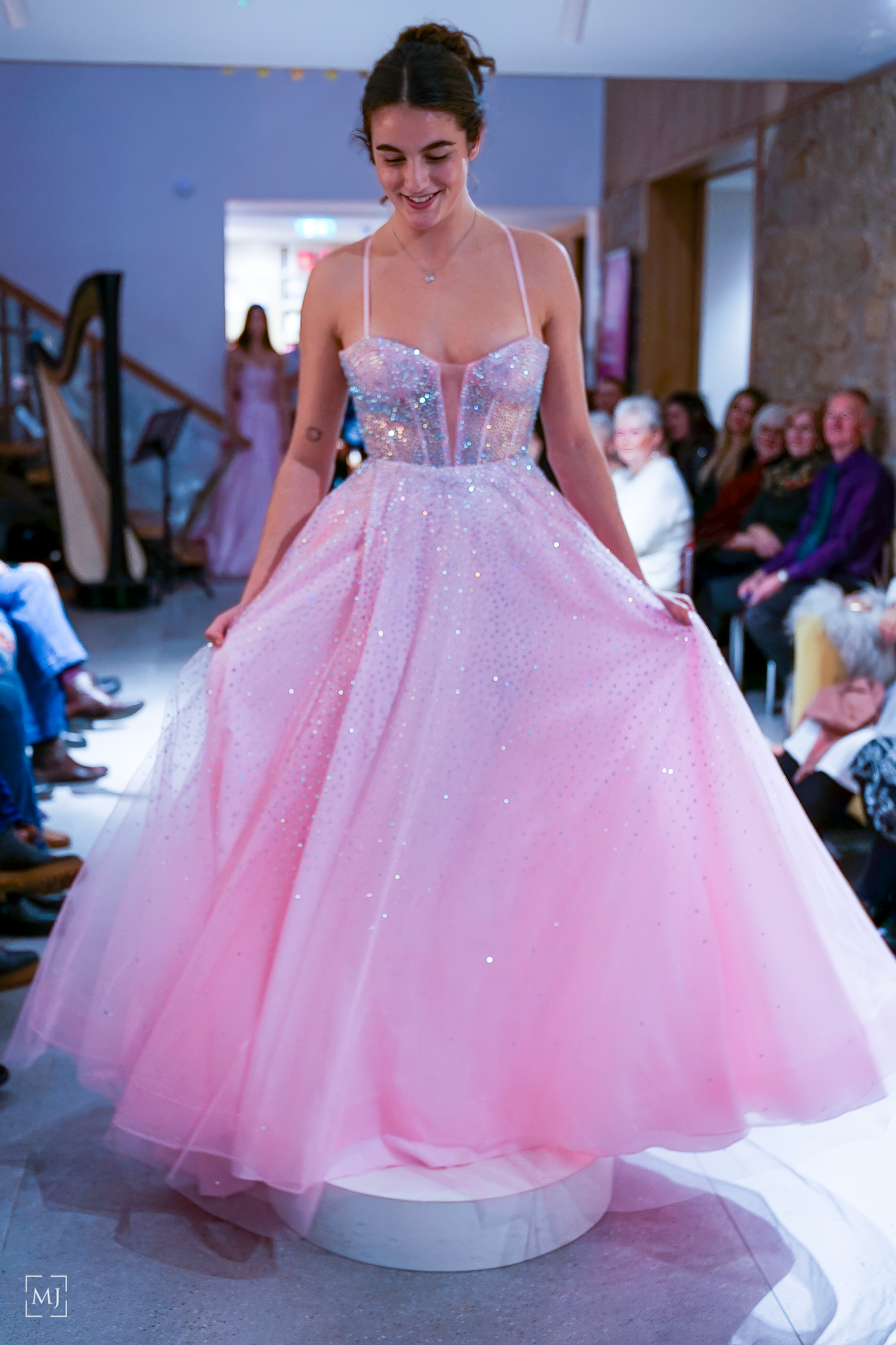 A model walks the runway in a pink princess ball gown with sparkly tulle and illusion neckline at a bridal fashion show.