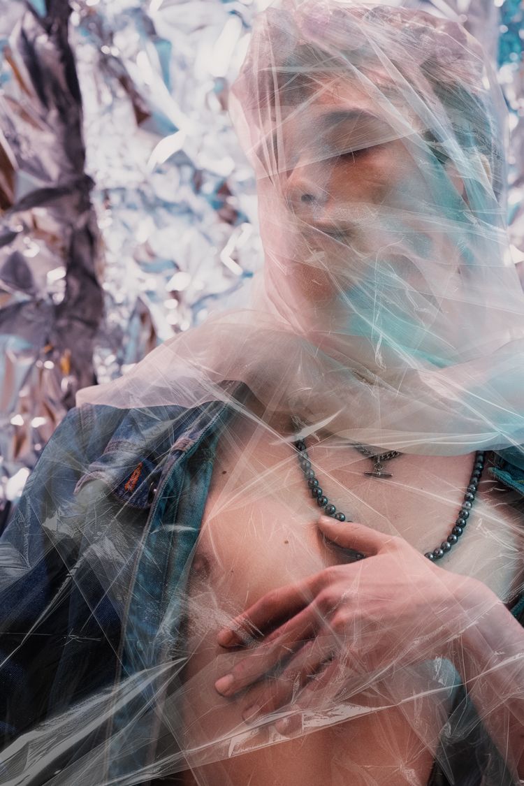 Ethereal portrait with translucent fabric overlay and beaded necklace.