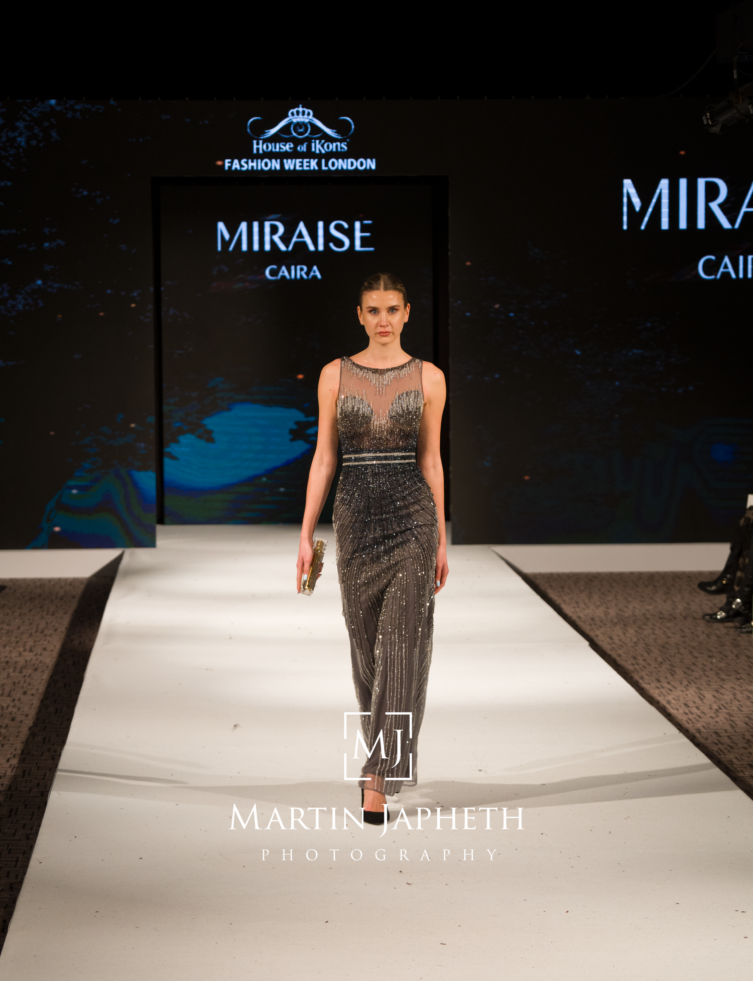 A model walks the runway in a shimmering gunmetal evening gown at the Miraise fashion show.