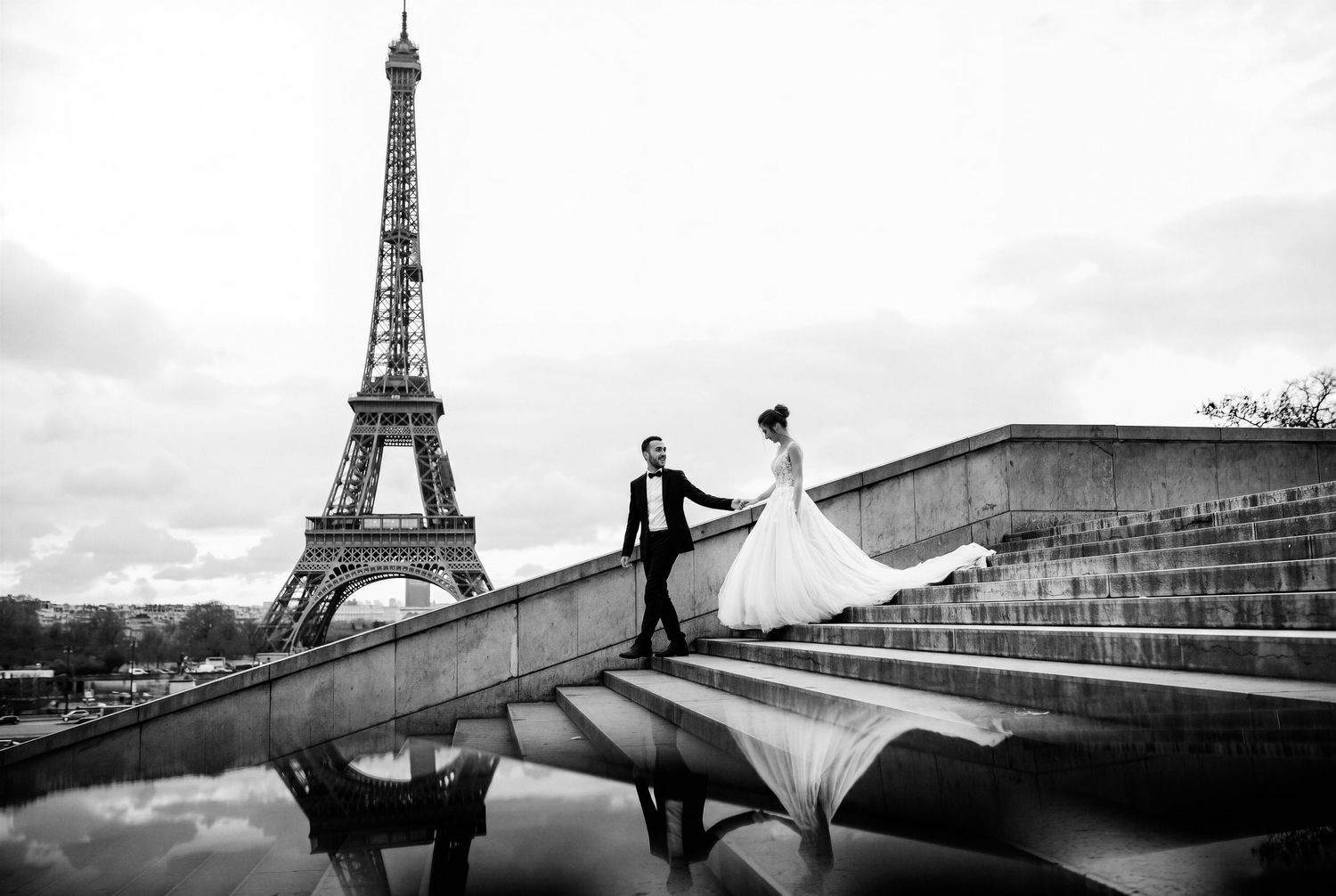 Black and white wedding photo of bride and groom near Eiffel Tower in Paris, France.