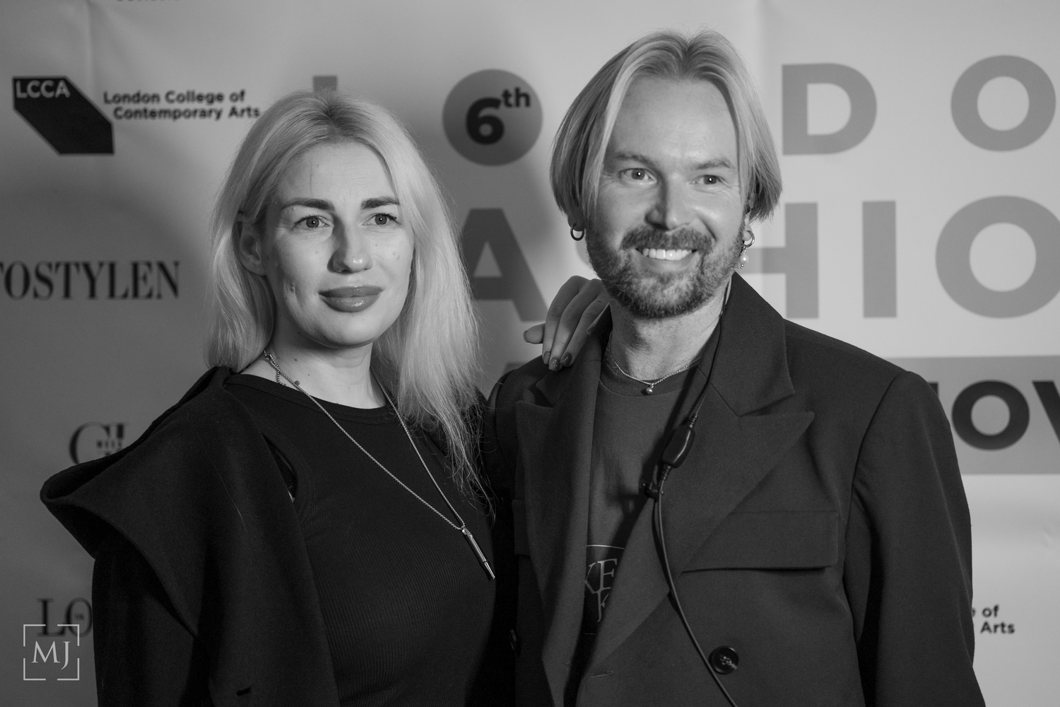 A black and white photo shows two people posing together at an event, wearing dark formal attire. Fashion Photographer Martin Japheth