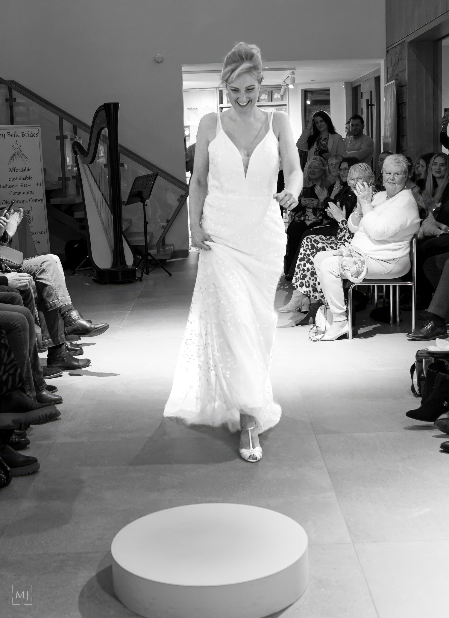 Models showcase elegant white wedding gowns on a circular runway during a bridal fashion show.