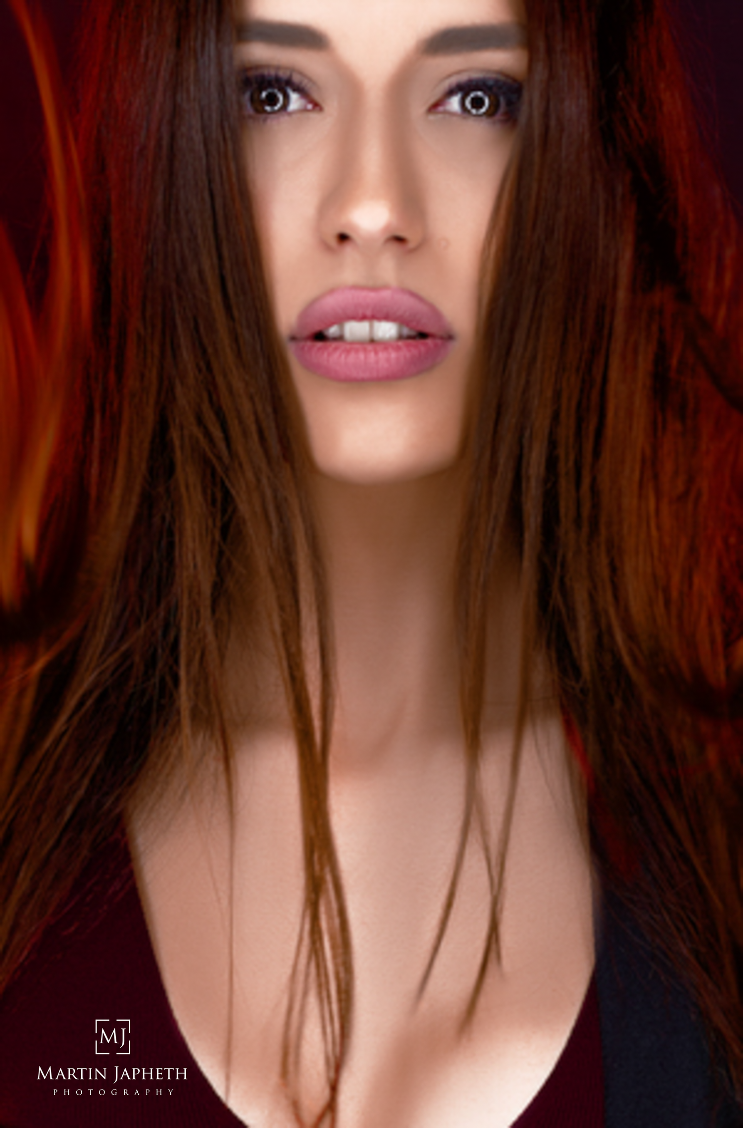 Close-up portrait of a woman with long red hair and striking eyes by Martin Japheth Photography.