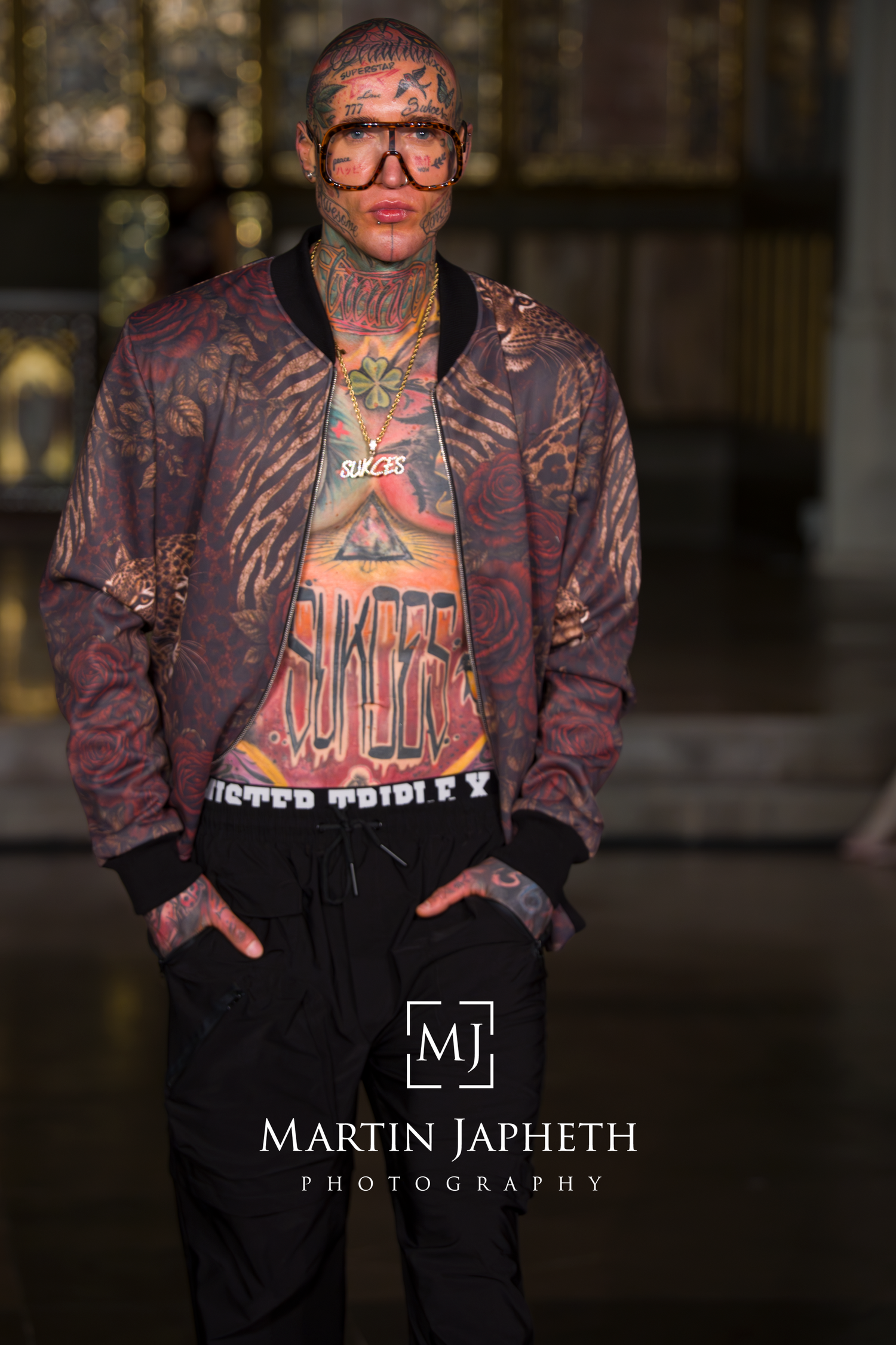 Fashion portrait of someone wearing patterned bomber jacket, Mister Triple X Model walks runway wearing black pants and tie-dye patterned