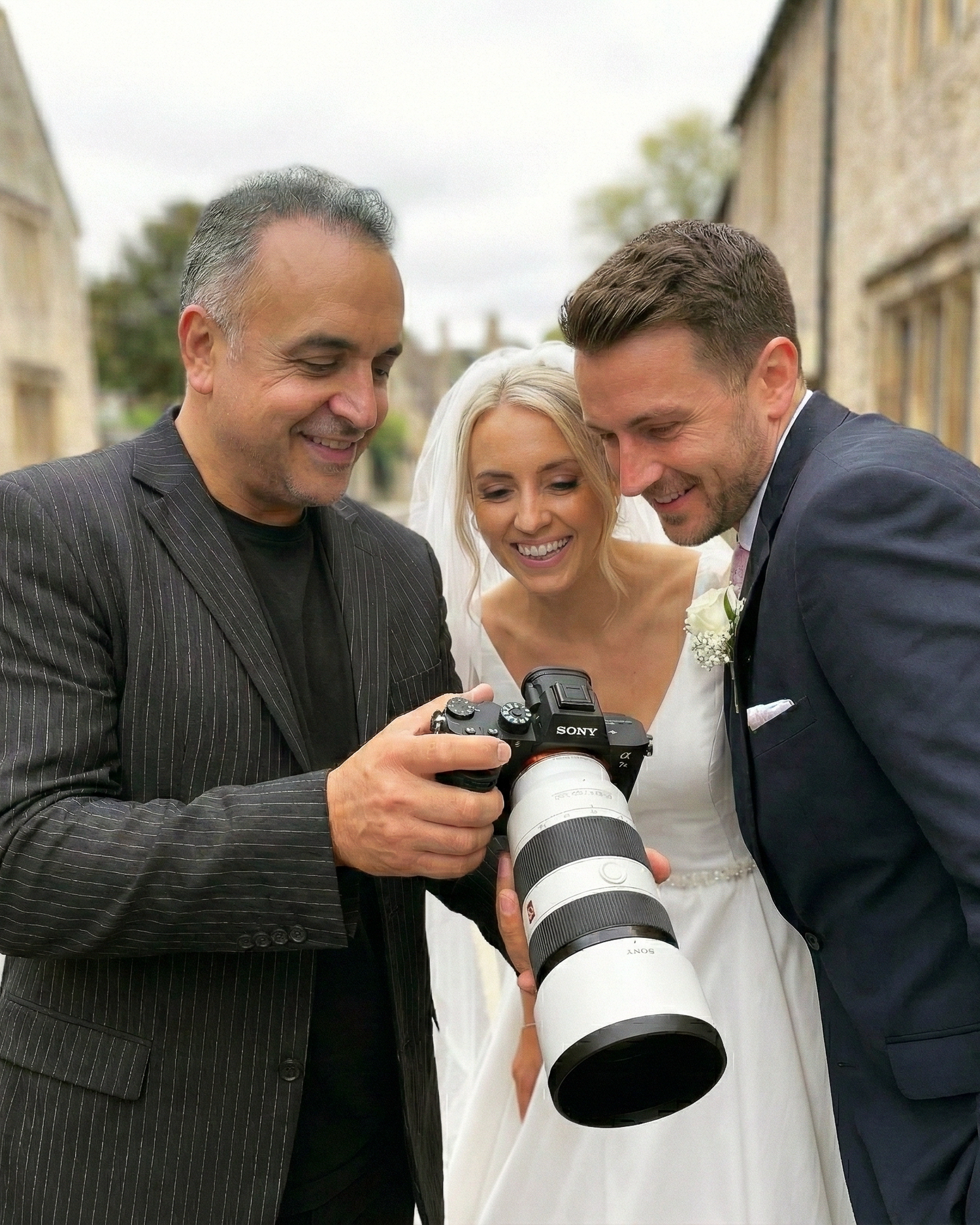 Wedding photographer showing captured images to couple on camera display.