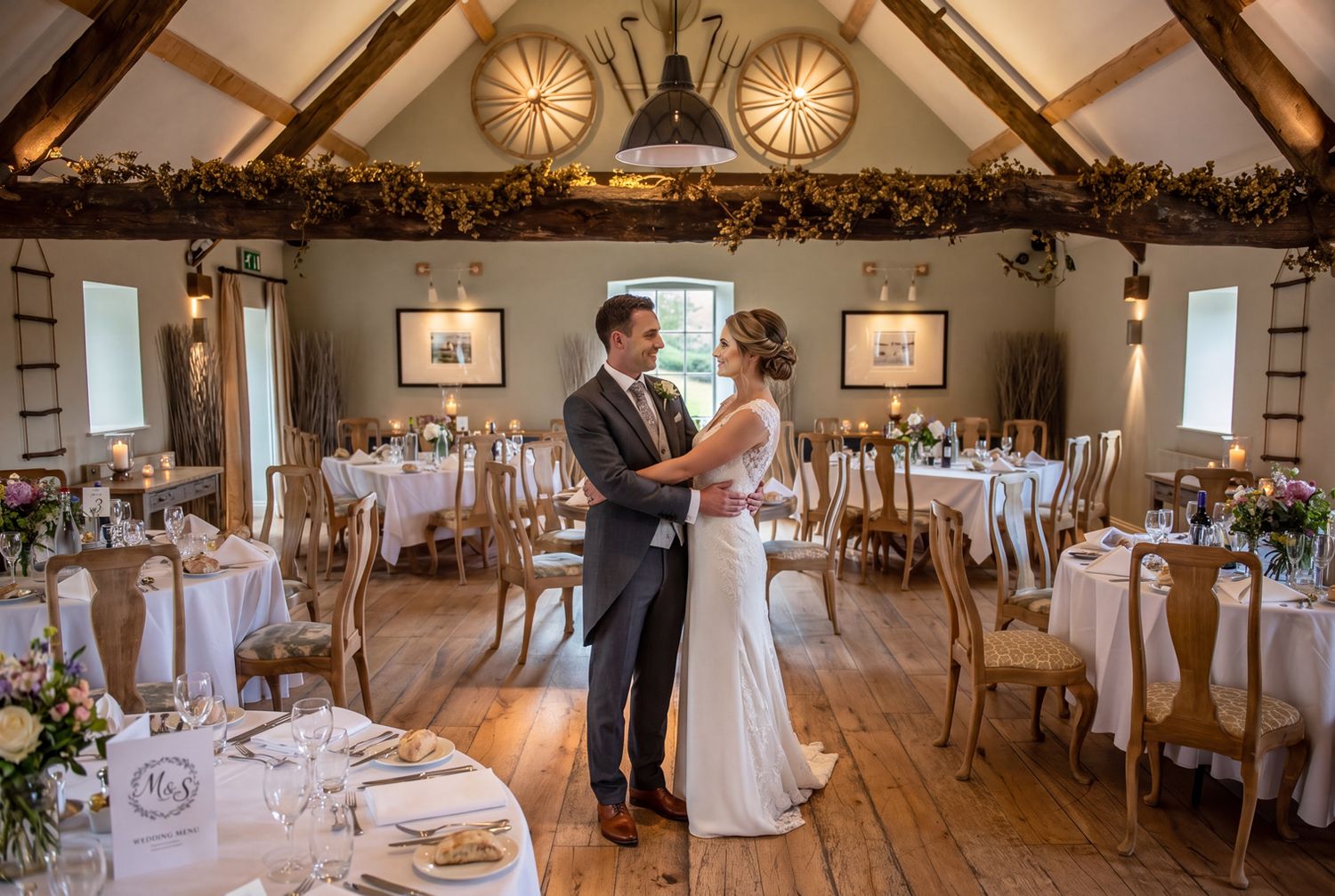 Bride and groom the Hayloft, Bodnant Welsh Foods wedding venue with wooden beams and candlelit tables. Martin Japheth Photography