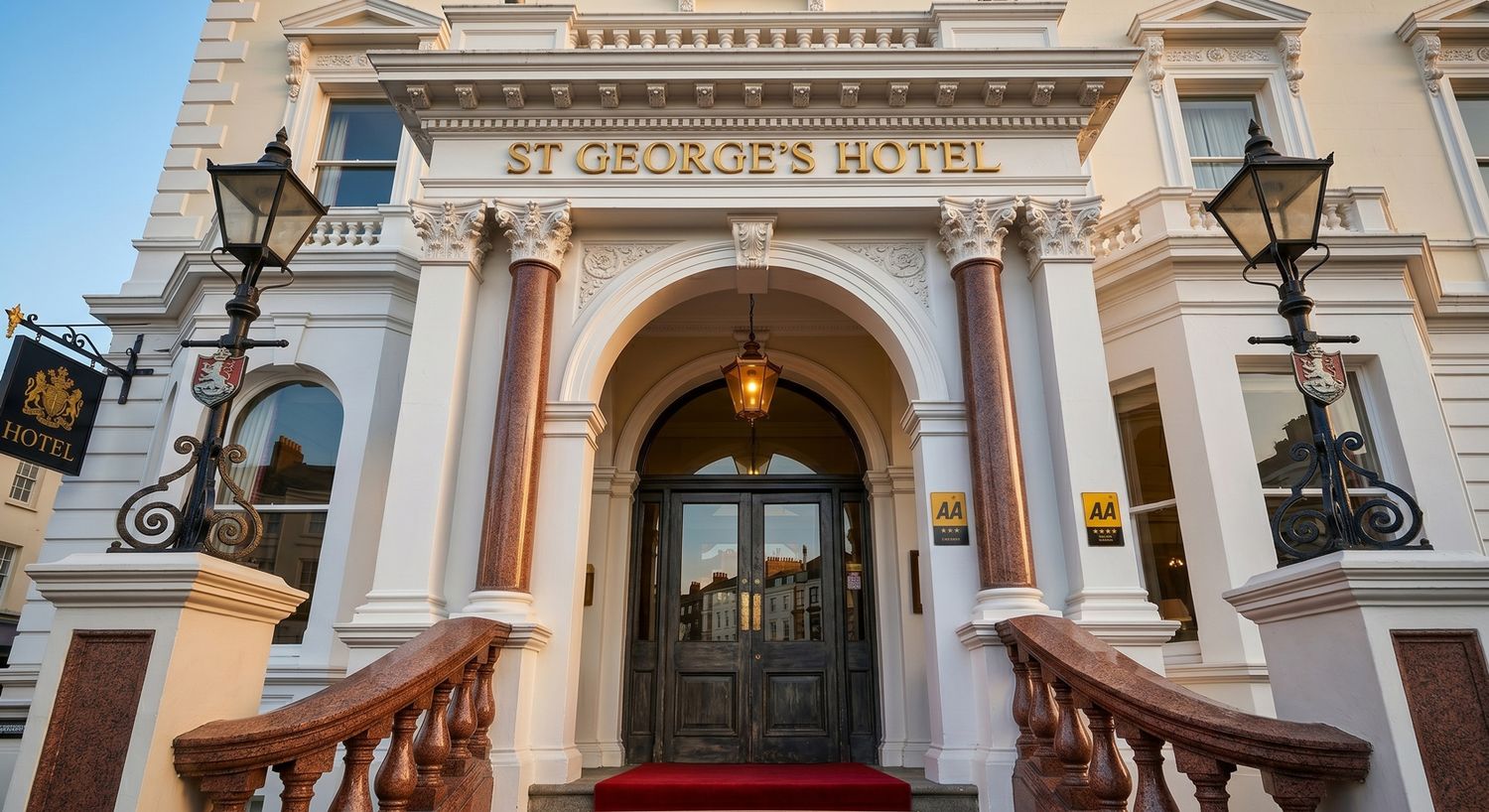 Elegant entrance of St George's Hotel featuring grand arched doorway, red carpet stairs, and ornate lamp posts.