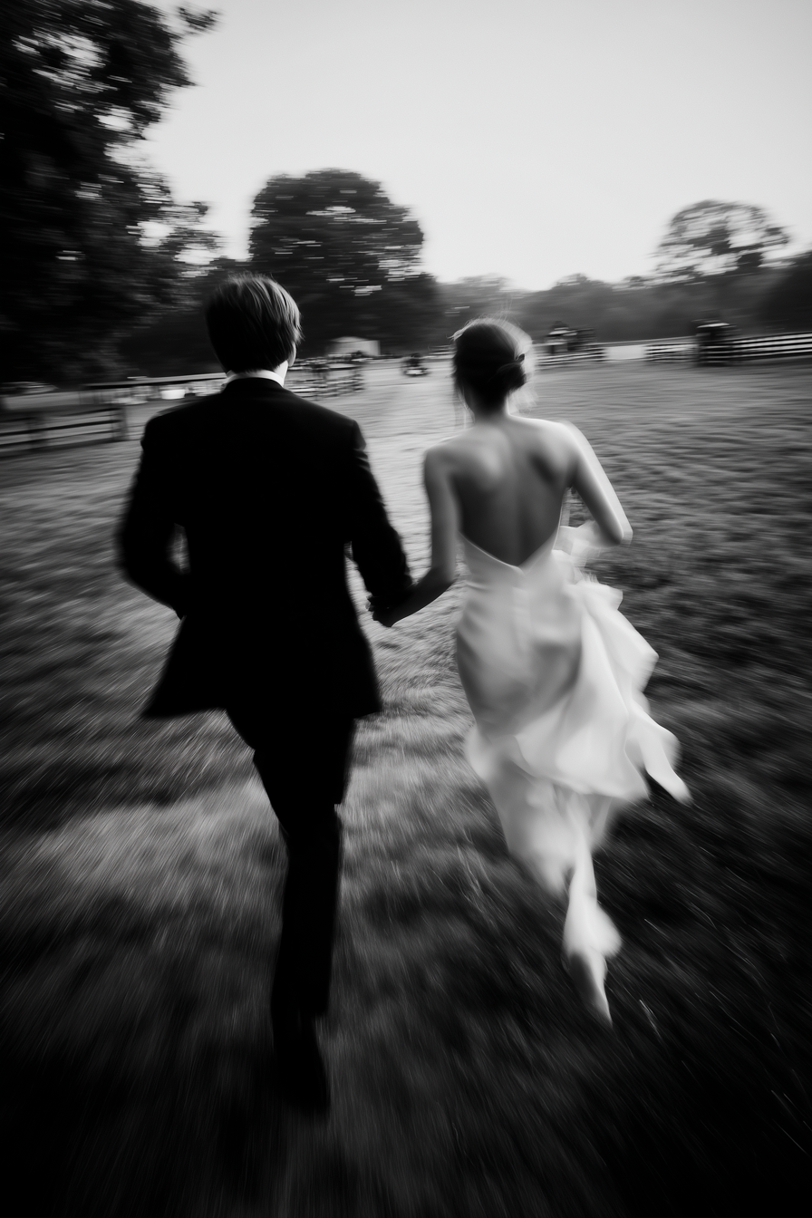 Black and white motion blur sequence shows a couple running through a field in wedding attire.