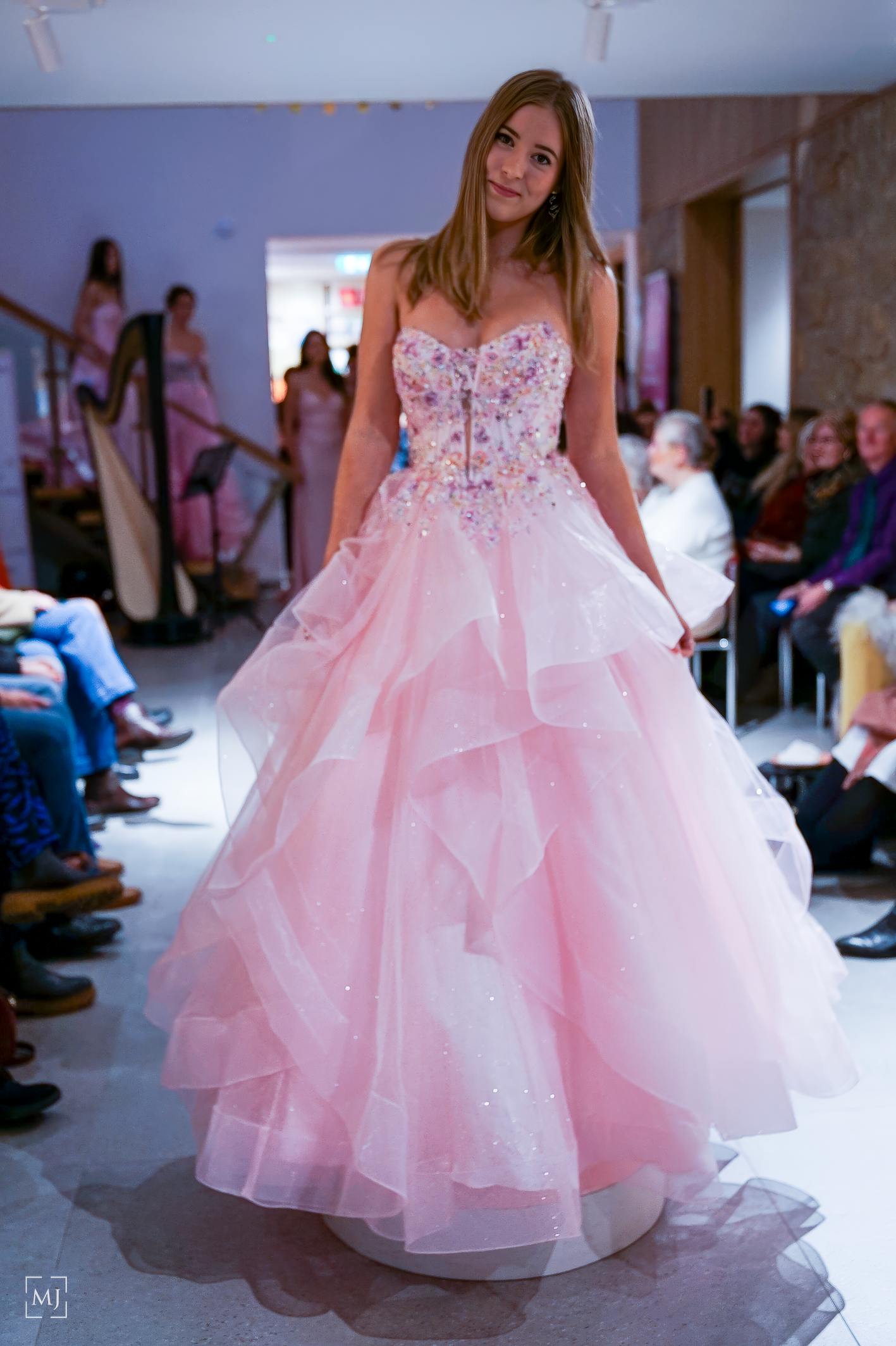 Pink and white layered tulle ball gown with crystal embellished bodice showcased on fashion runway.