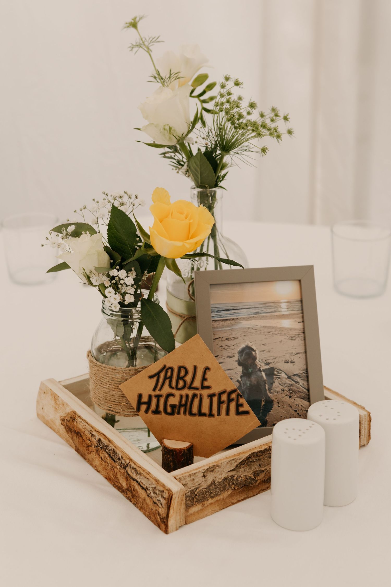 Wedding table decor featuring wooden boxes with yellow flowers and table number signs.