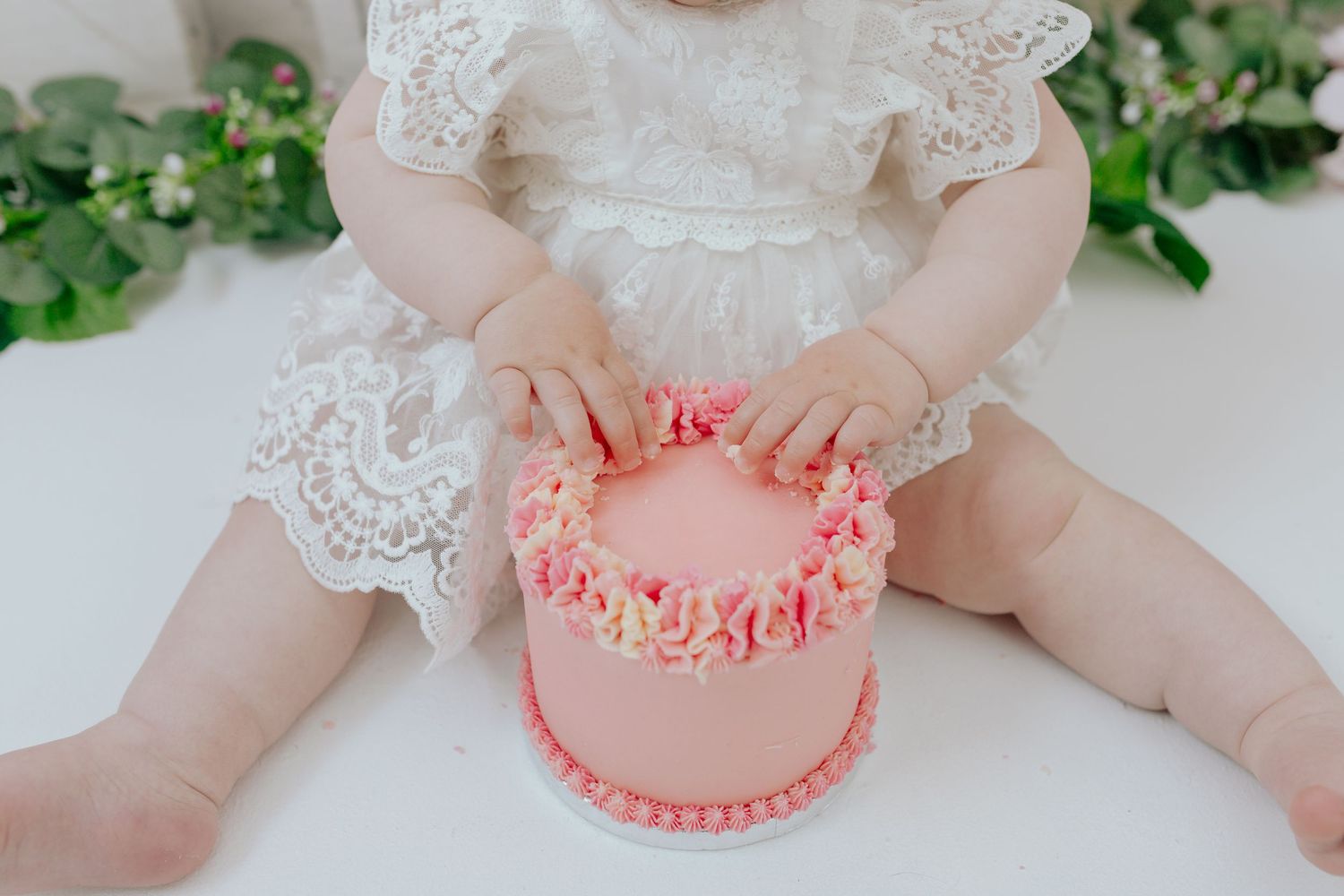Close-up of small pink birthday cake with delicate frosting details.