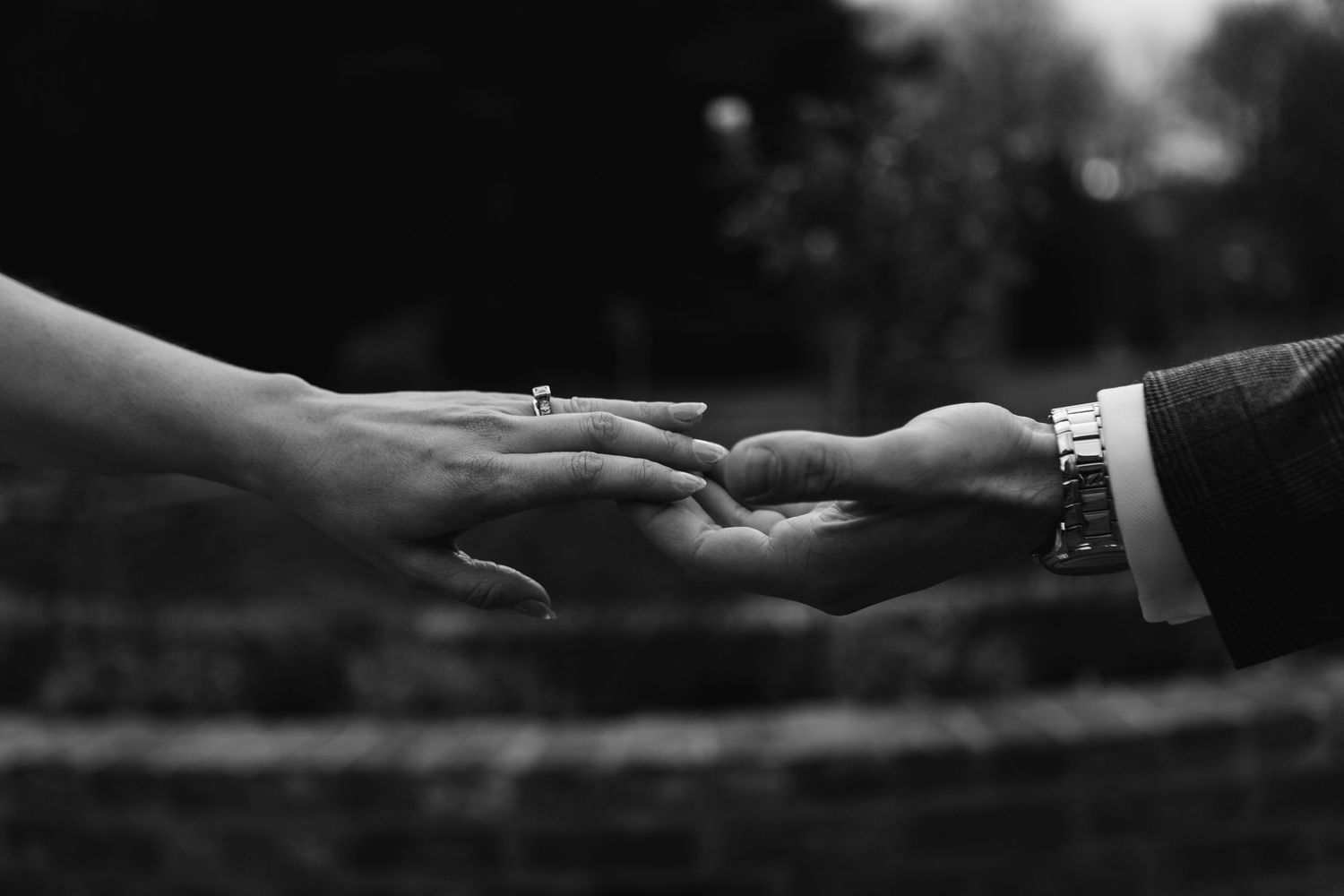 Black and white close-up of hands reaching toward each other.