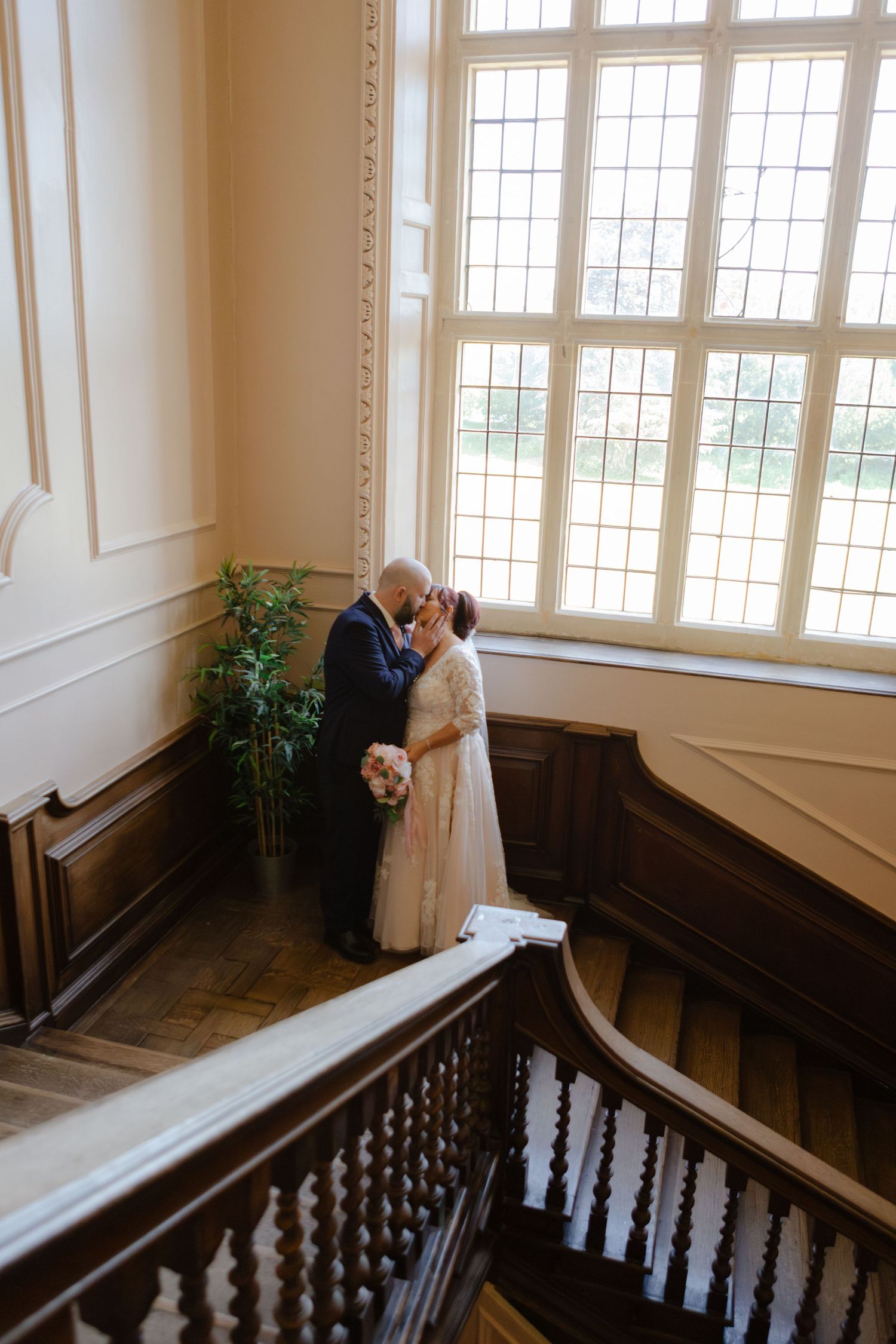 Elegant staircase with white walls and large windows in wedding venue.