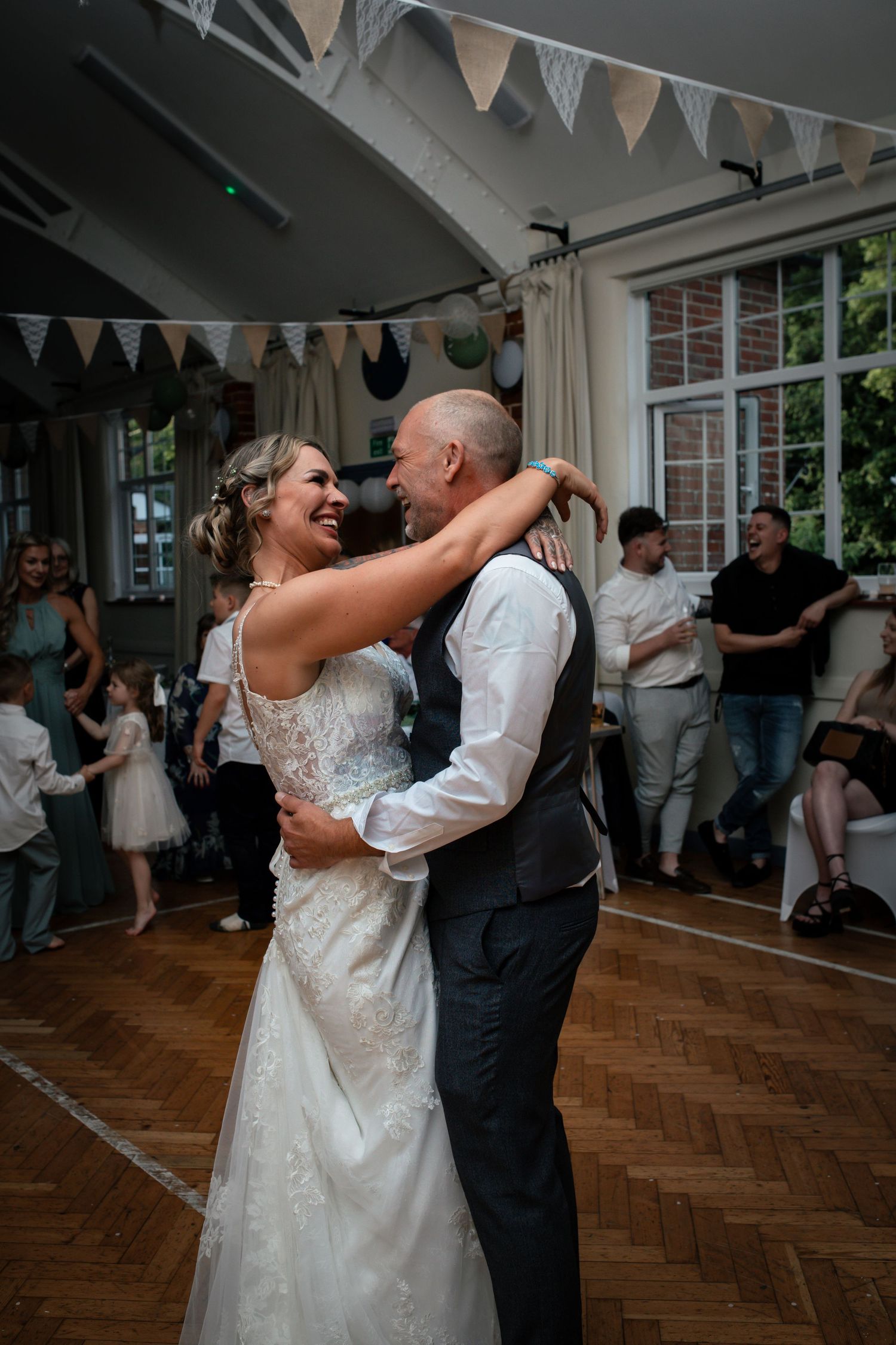 Wedding couple dances together under bunting decorations in a rustic venue.