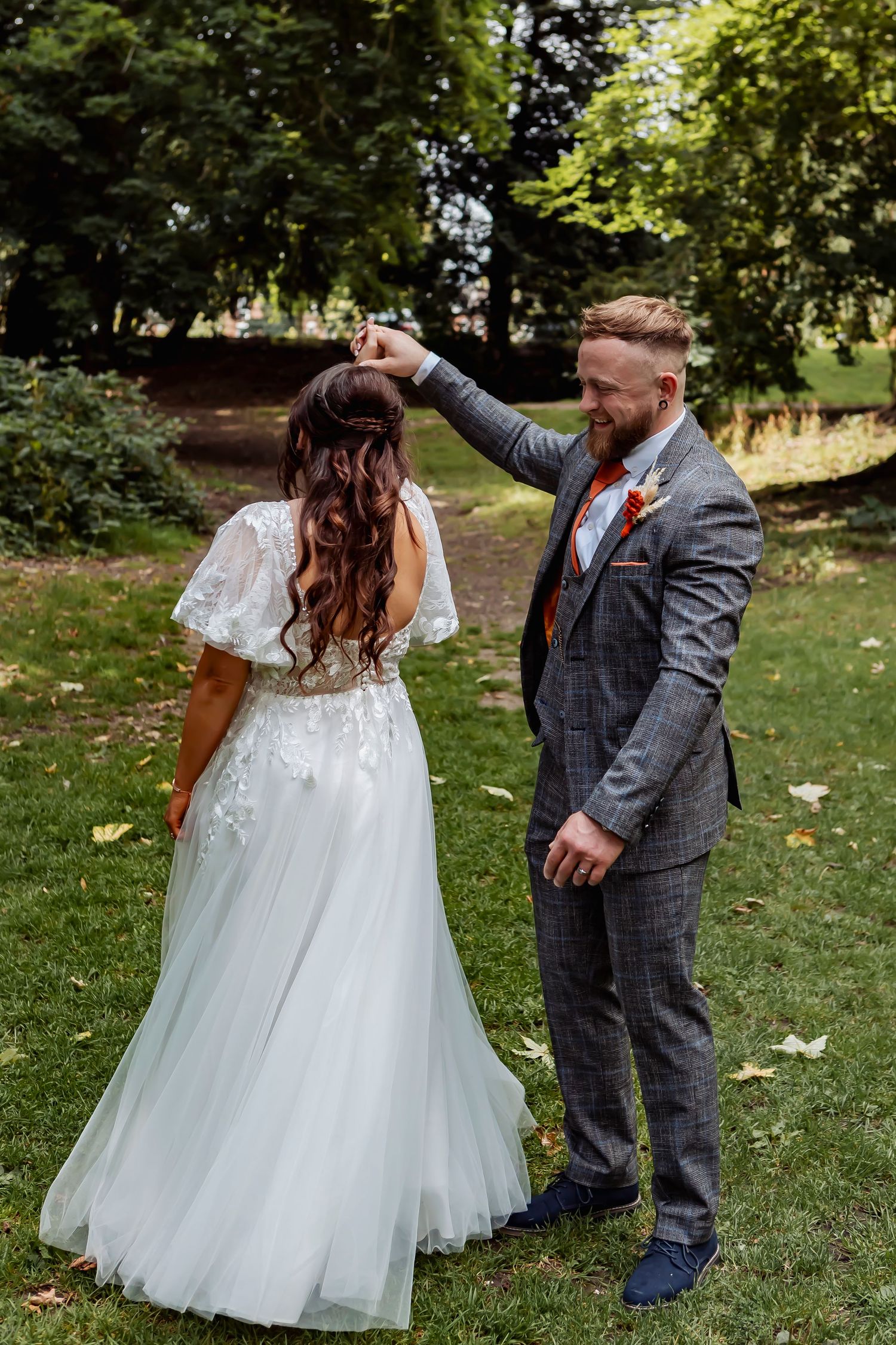 Wedding couple dancing and twirling in a garden setting with the bride's white dress flowing.